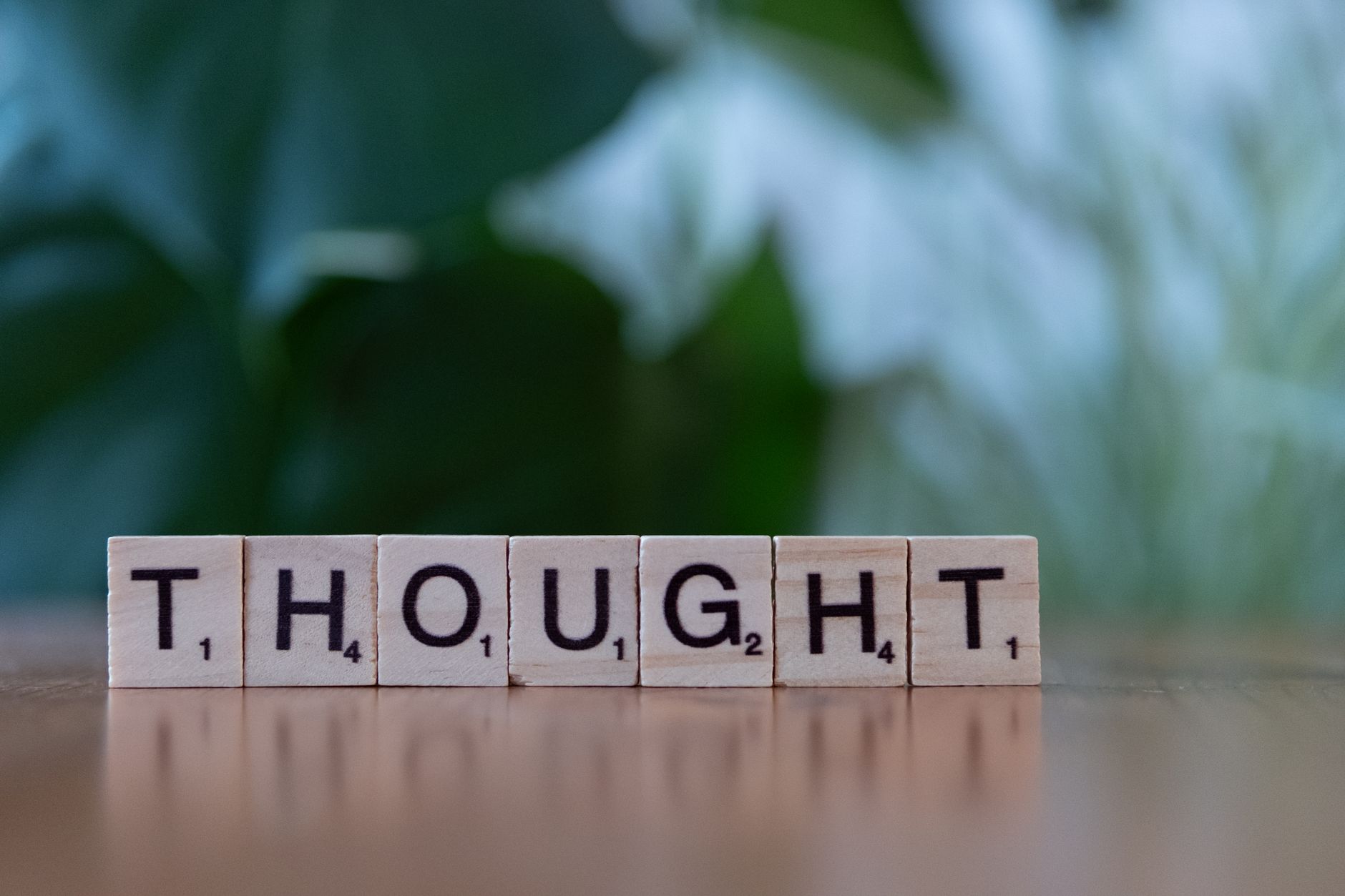 Wooden blocks spelling 'THOUGHT' on a table with a blurred background, conveying ideas and introspection.
