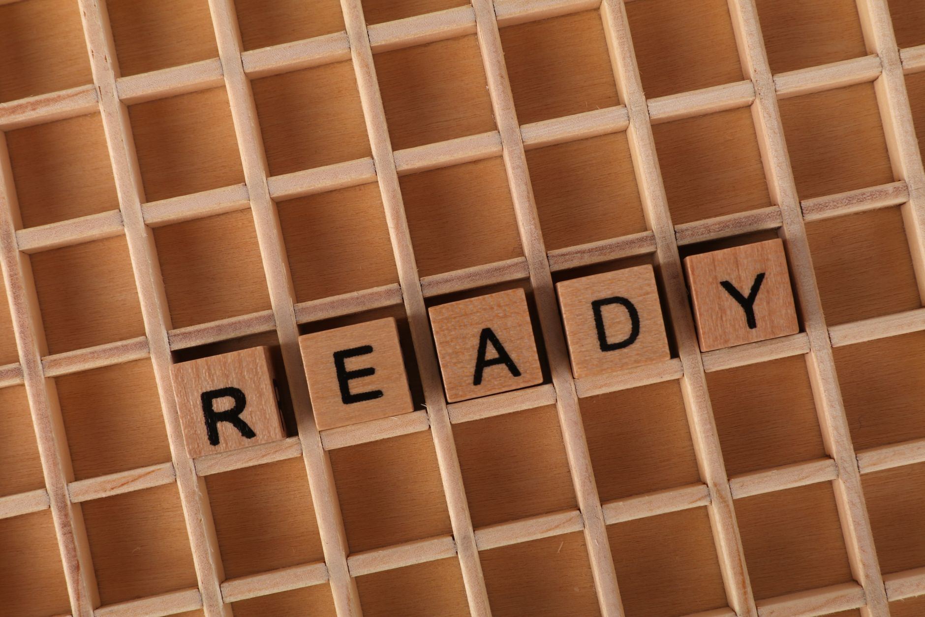 Wooden letter blocks on a grid form the word READY, symbolizing preparation and readiness.