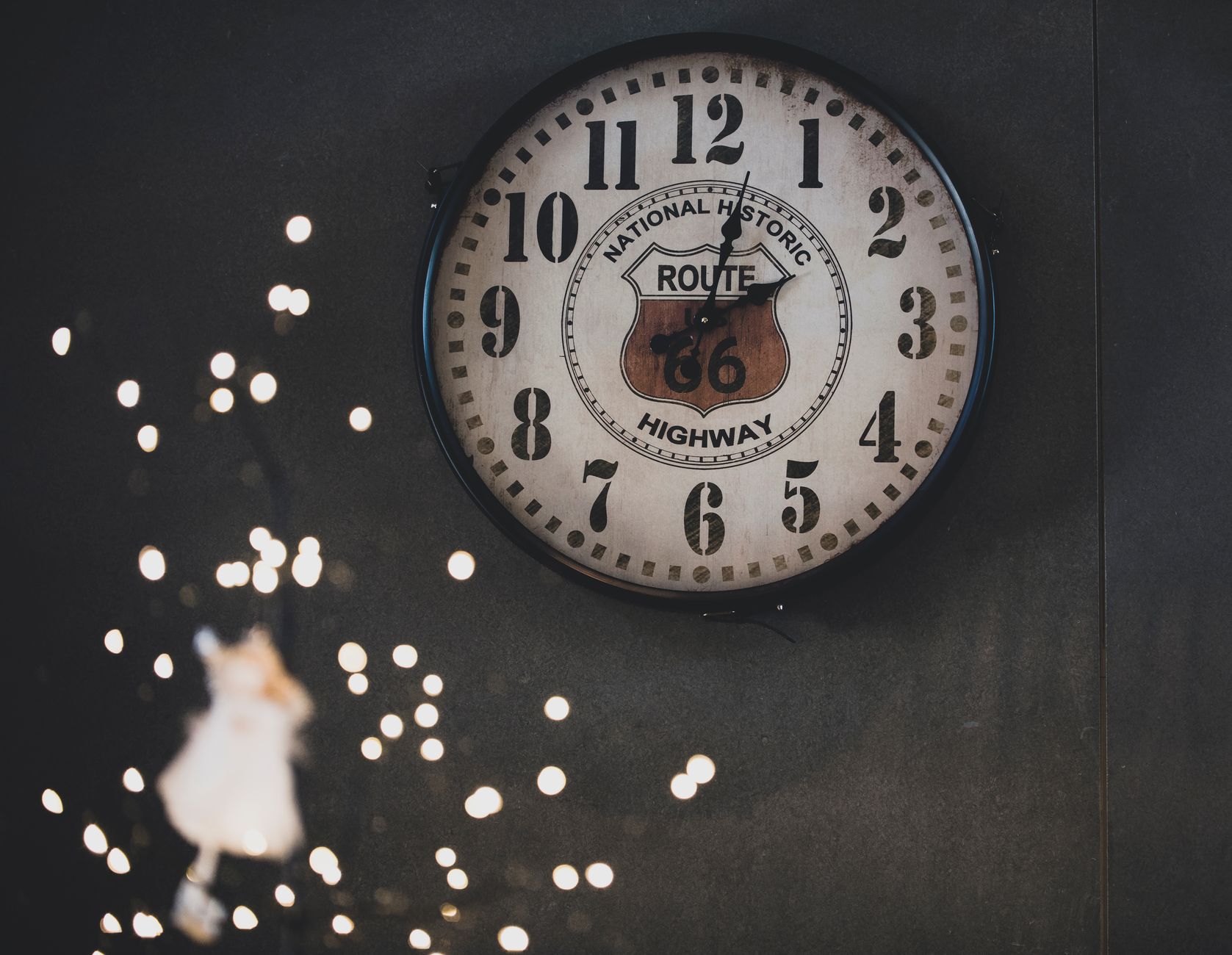 A retro Route 66 wall clock surrounded by soft, magical bokeh lighting.