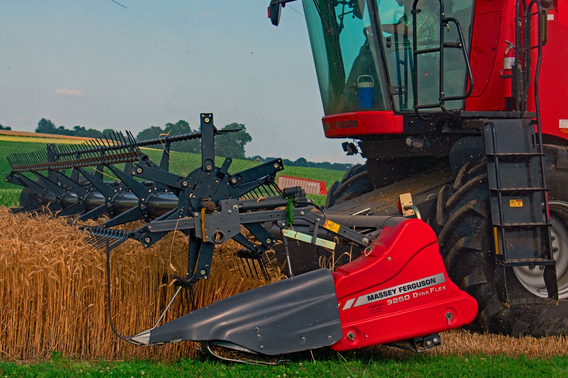 A red combine harvester operates in a Pennsylvania wheat field during a summer harvest.
