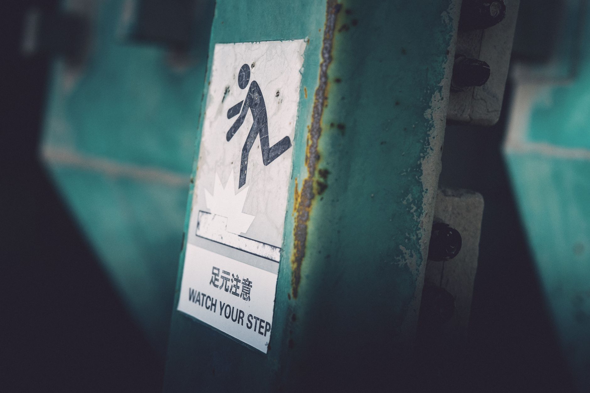 Dimly lit caution sign indicating 'Watch Your Step' in urban setting.