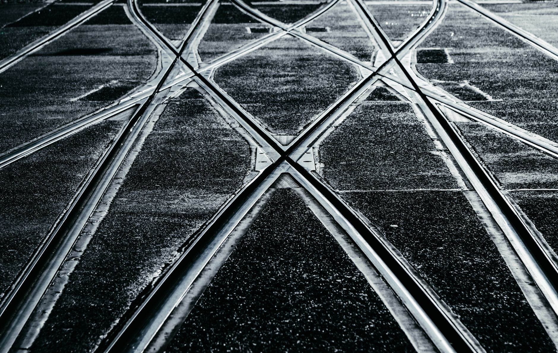 Black and white photo of intersecting train tracks captured in a dramatic light.
