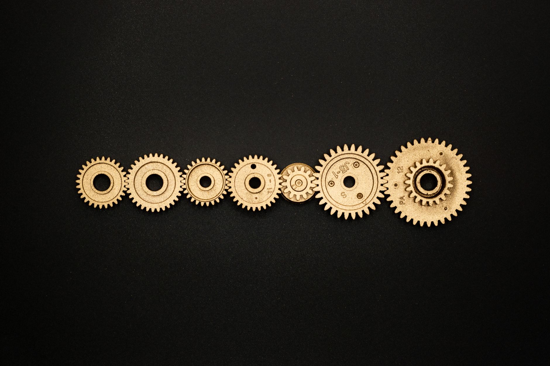 An artistic arrangement of golden gears on a dark backdrop, symbolizing mechanics and cooperation.
