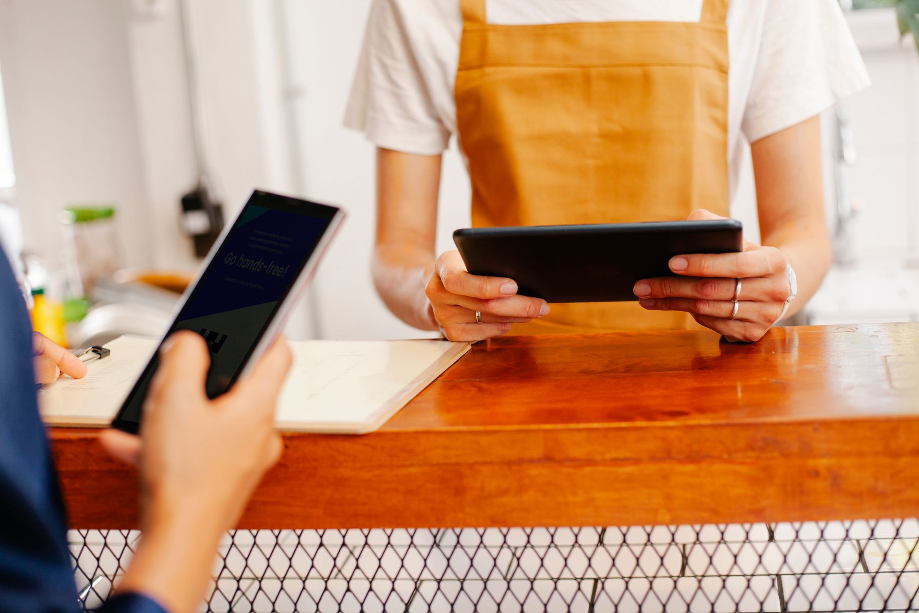 Crop anonymous female colleagues surfing internet on cellphone with black screen and tablet in cafe
