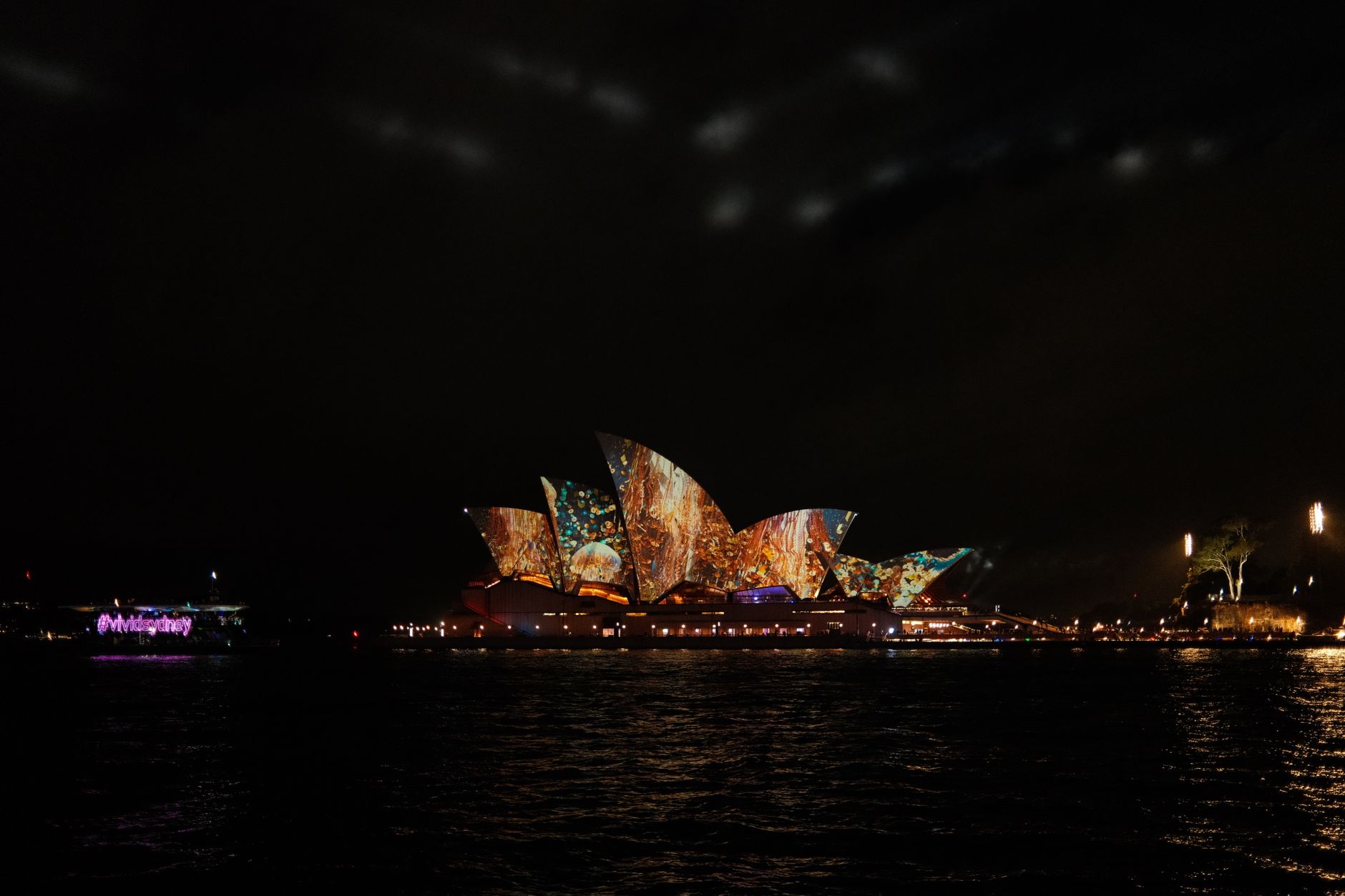 Sydney Opera House illuminated at night with vibrant light projections.