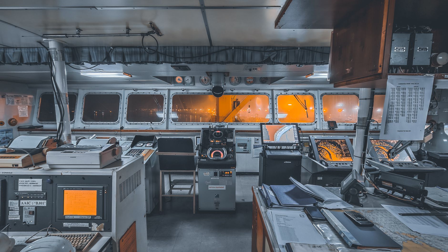 Interior view of a ship's control bridge with navigation technology and machinery.