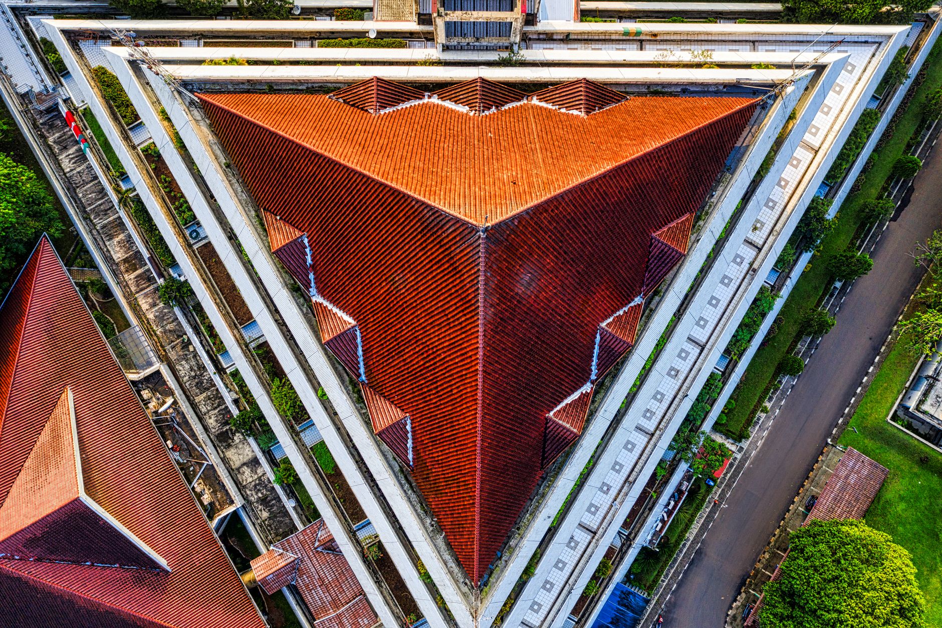 Striking aerial view of a triangular red roof at a university in Indonesia, showcasing unique architectural design.
