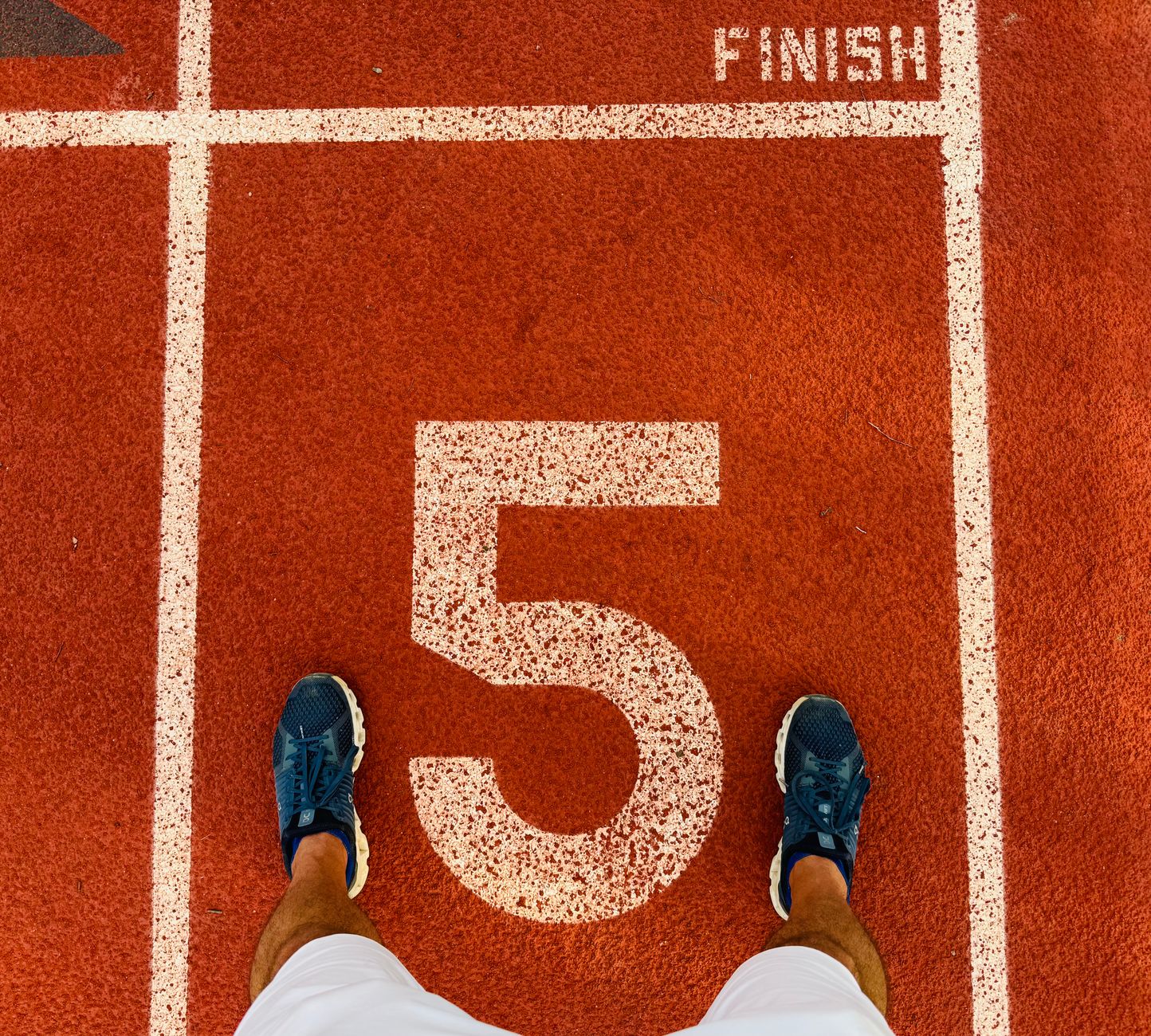 Runner's feet on track lane 5 at the finish line, symbolizing completion and success.