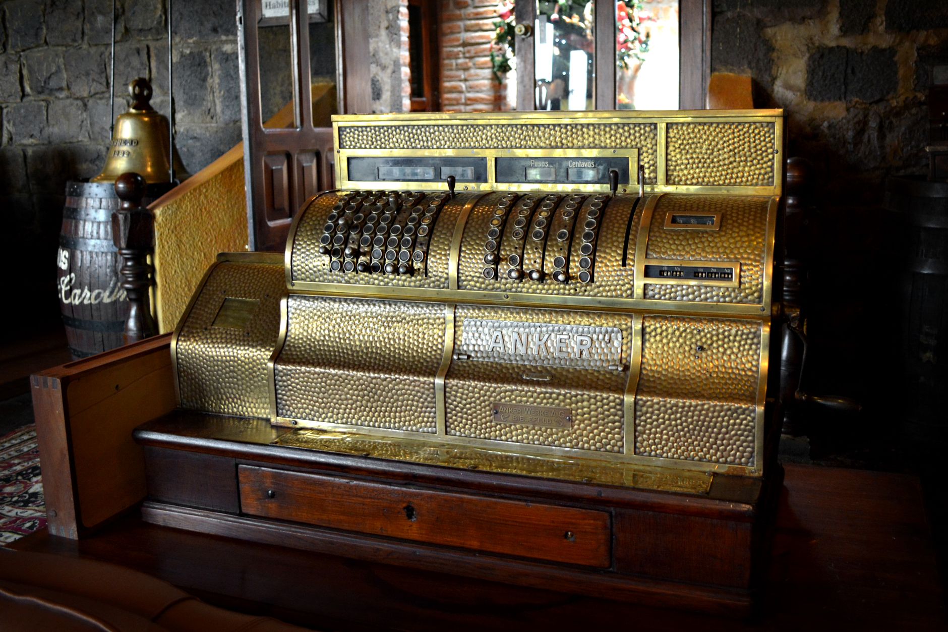 A beautifully preserved vintage brass cash register displayed in a rustic, wooden interior.