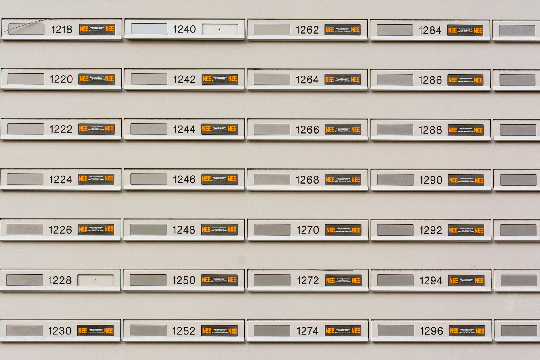 Row of modern mailboxes with numbers in an urban setting, featuring a pattern.