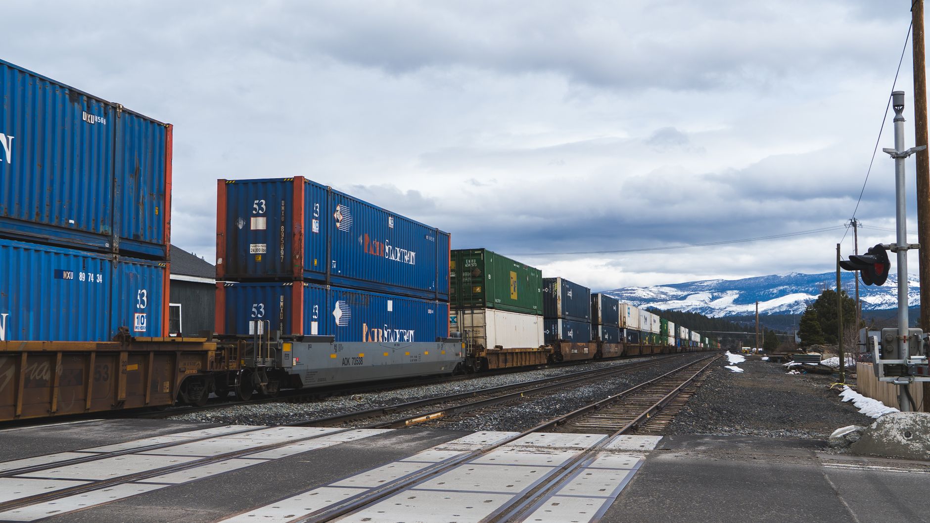 Long freight train passing through snowy Truckee, California with mountains in the background.