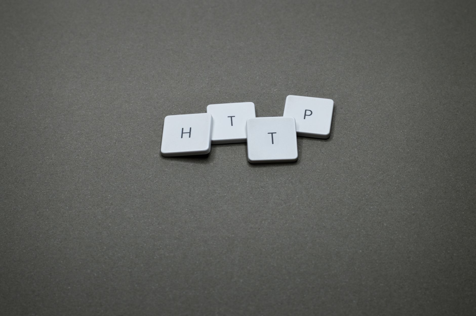 High-angle photo of keyboard tiles spelling HTTP on a dark background.