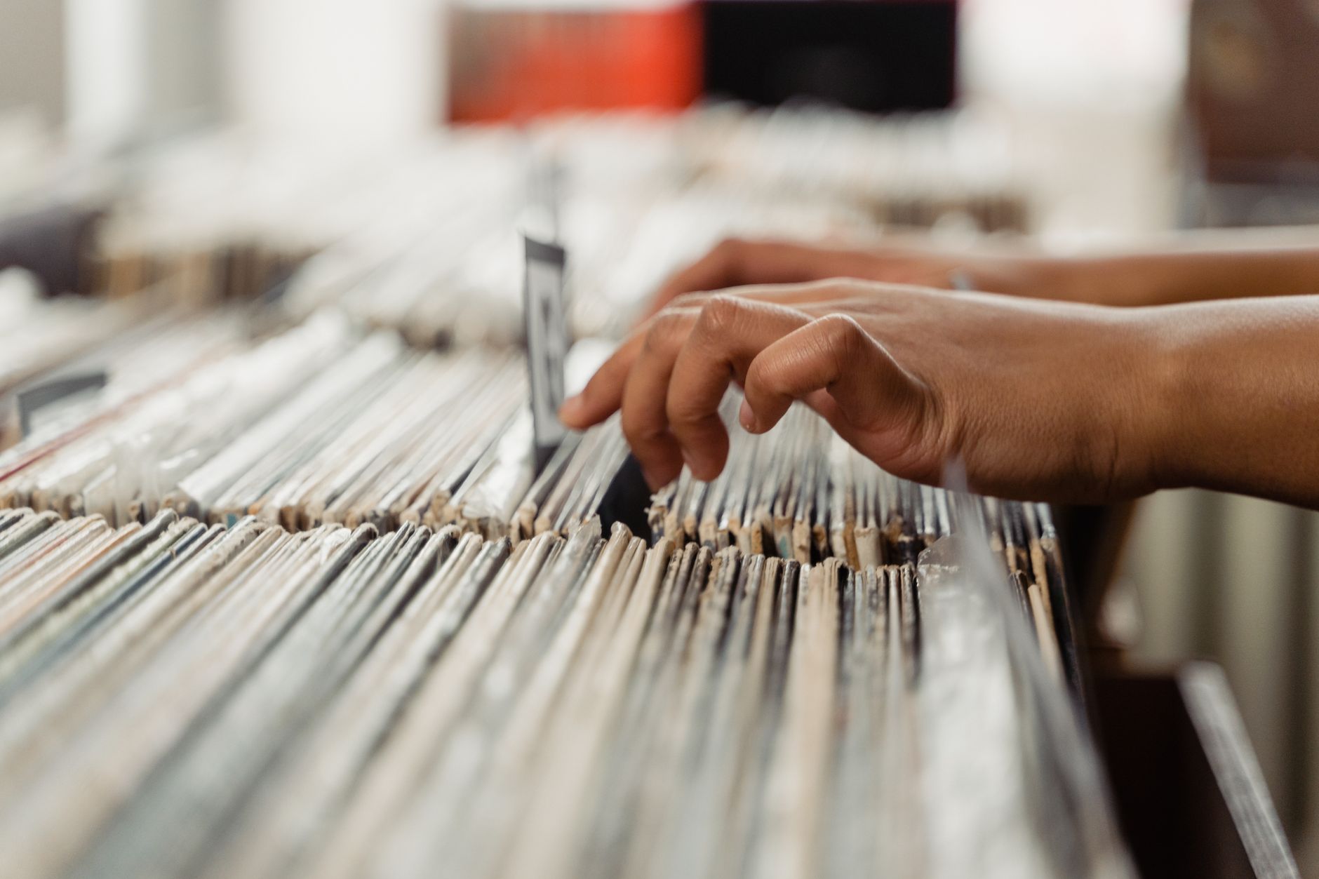 Close-up of hands searching through vinyl records, depicting a personal music shopping experience.