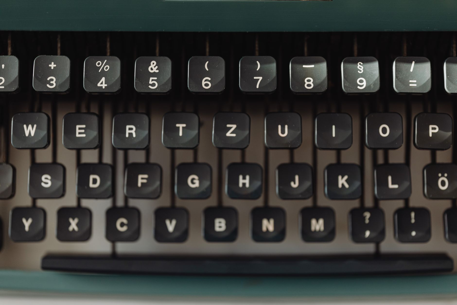 Close-up view of a black vintage typewriter keyboard with white keys showing letters and symbols.