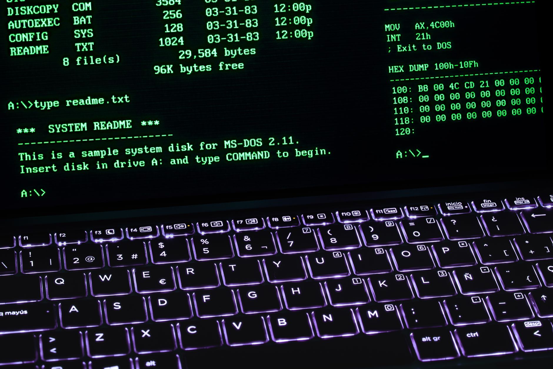A classic MS-DOS terminal screen displayed on a laptop keyboard with vivid illumination.