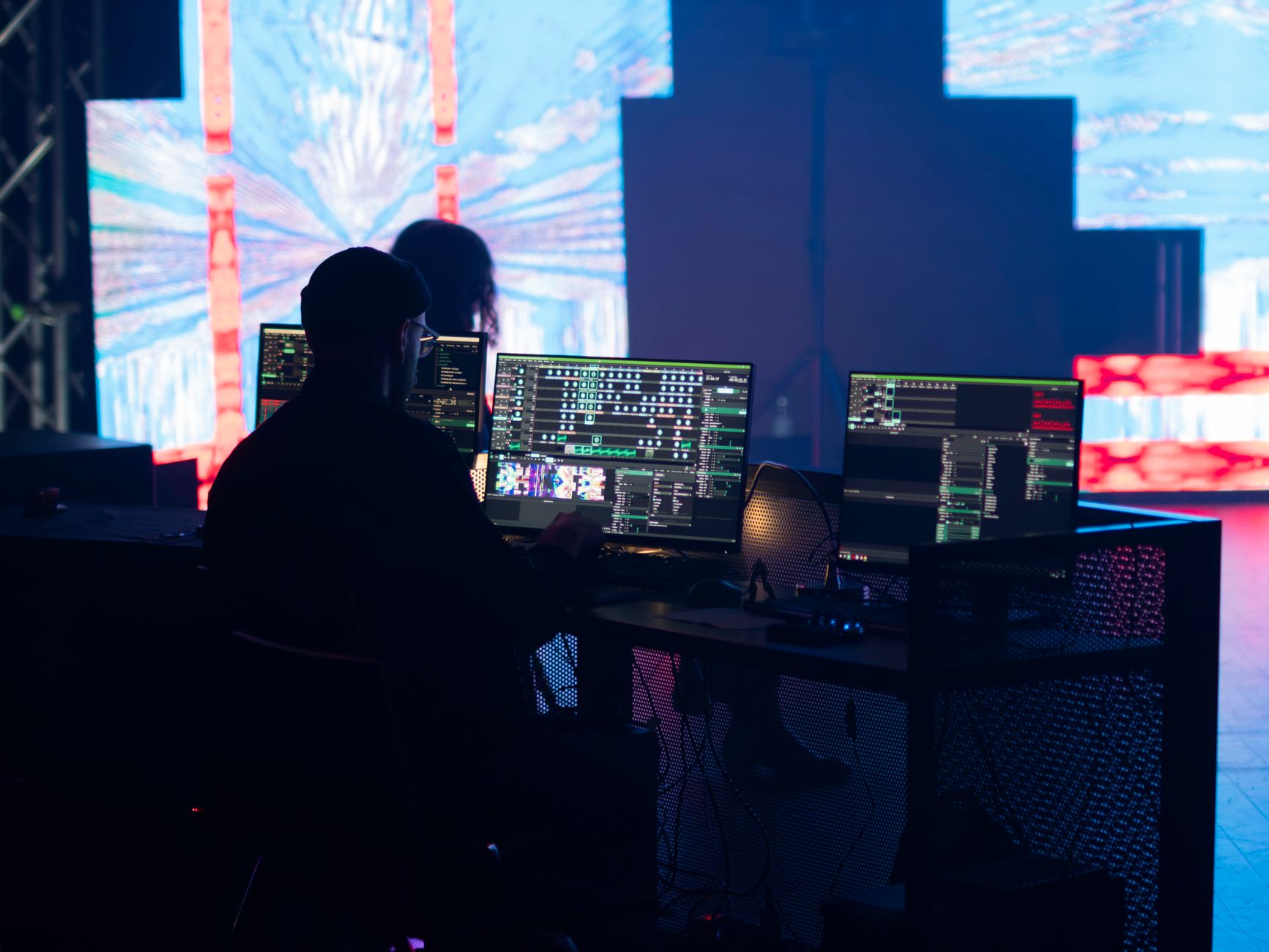 A stage technician monitors multimedia displays during a live event setup.