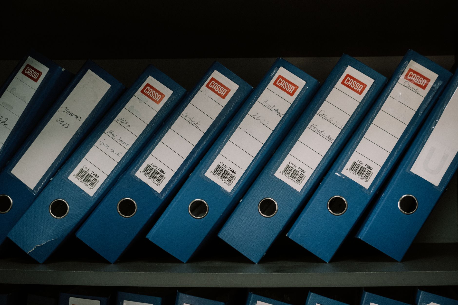 Neatly arranged blue office binders labeled with dates and names for organized storage.