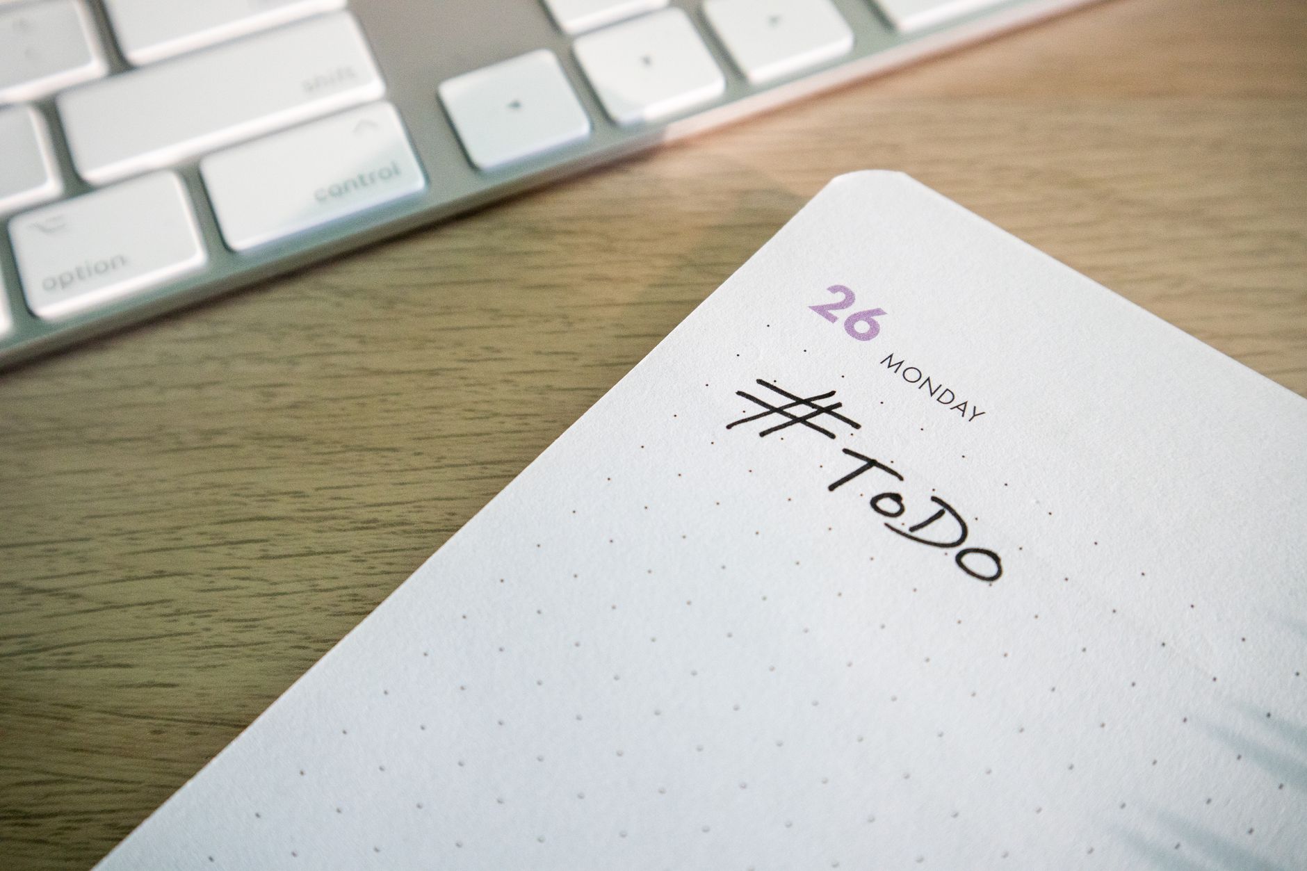 Close-up of a to-do list next to a computer keyboard on a desk.