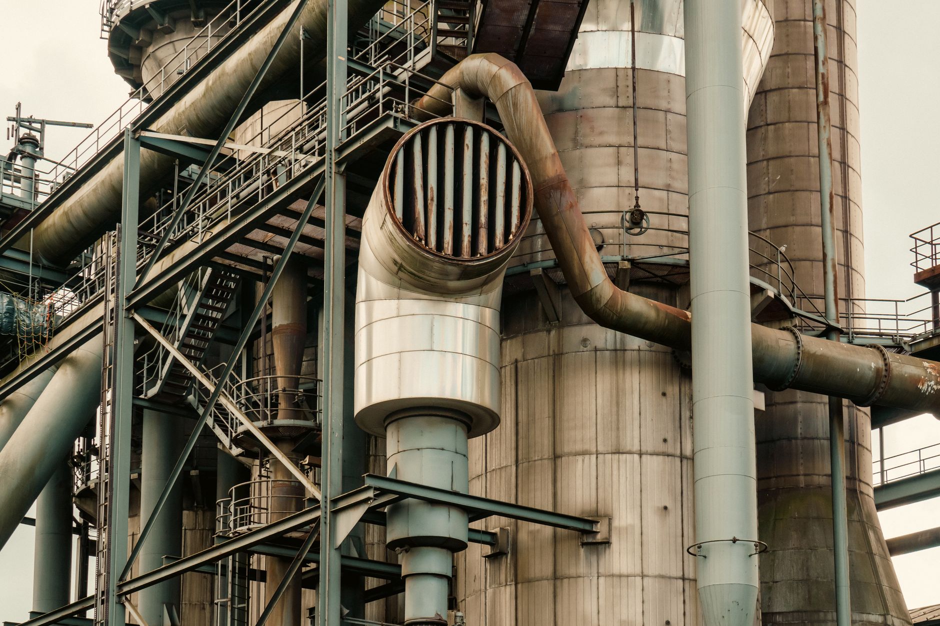 Close-up of industrial factory pipes and metal structures creating a complex machinery scene.