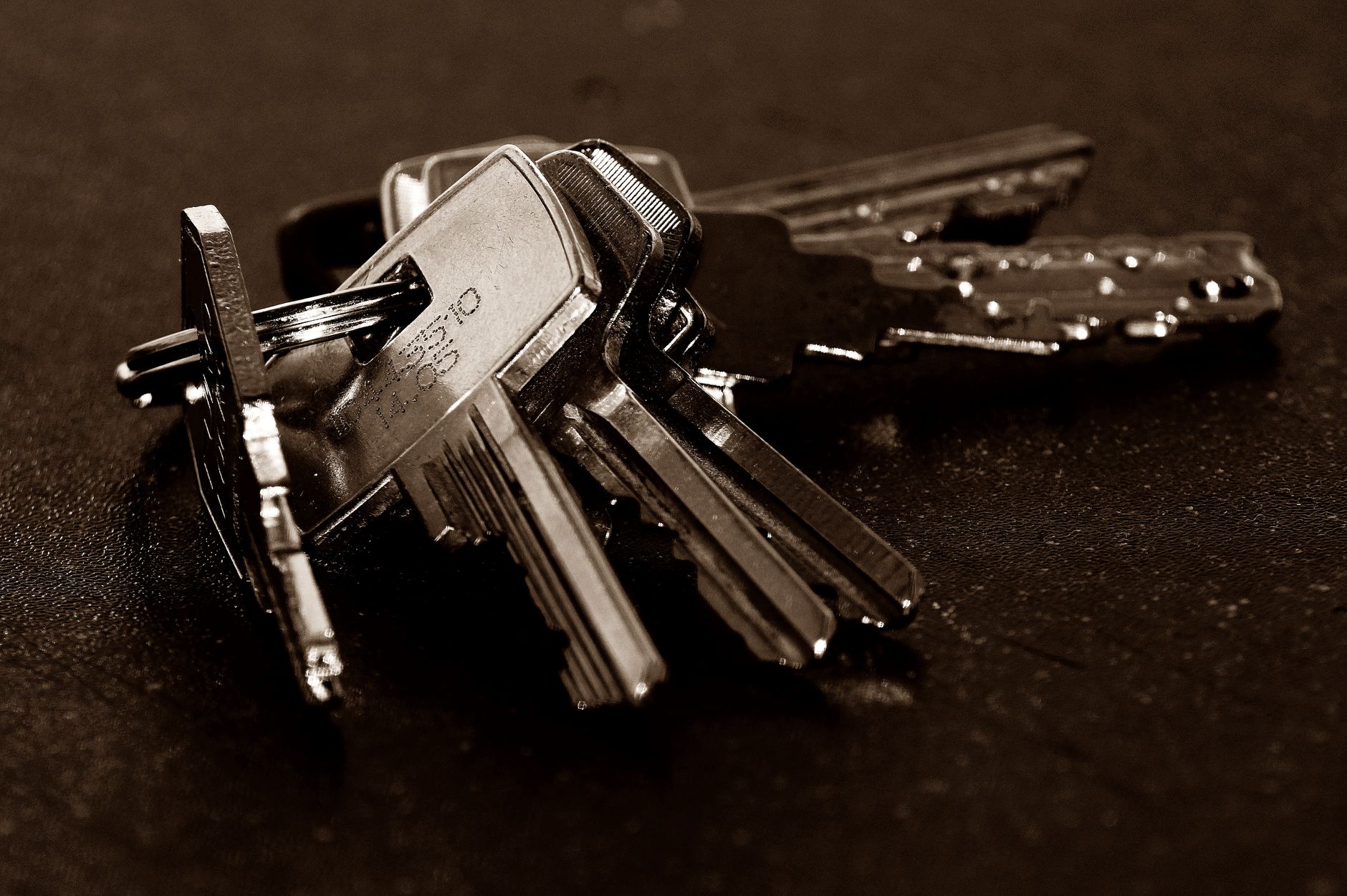A detailed close-up of a bunch of metallic keys resting on a dark textured surface.