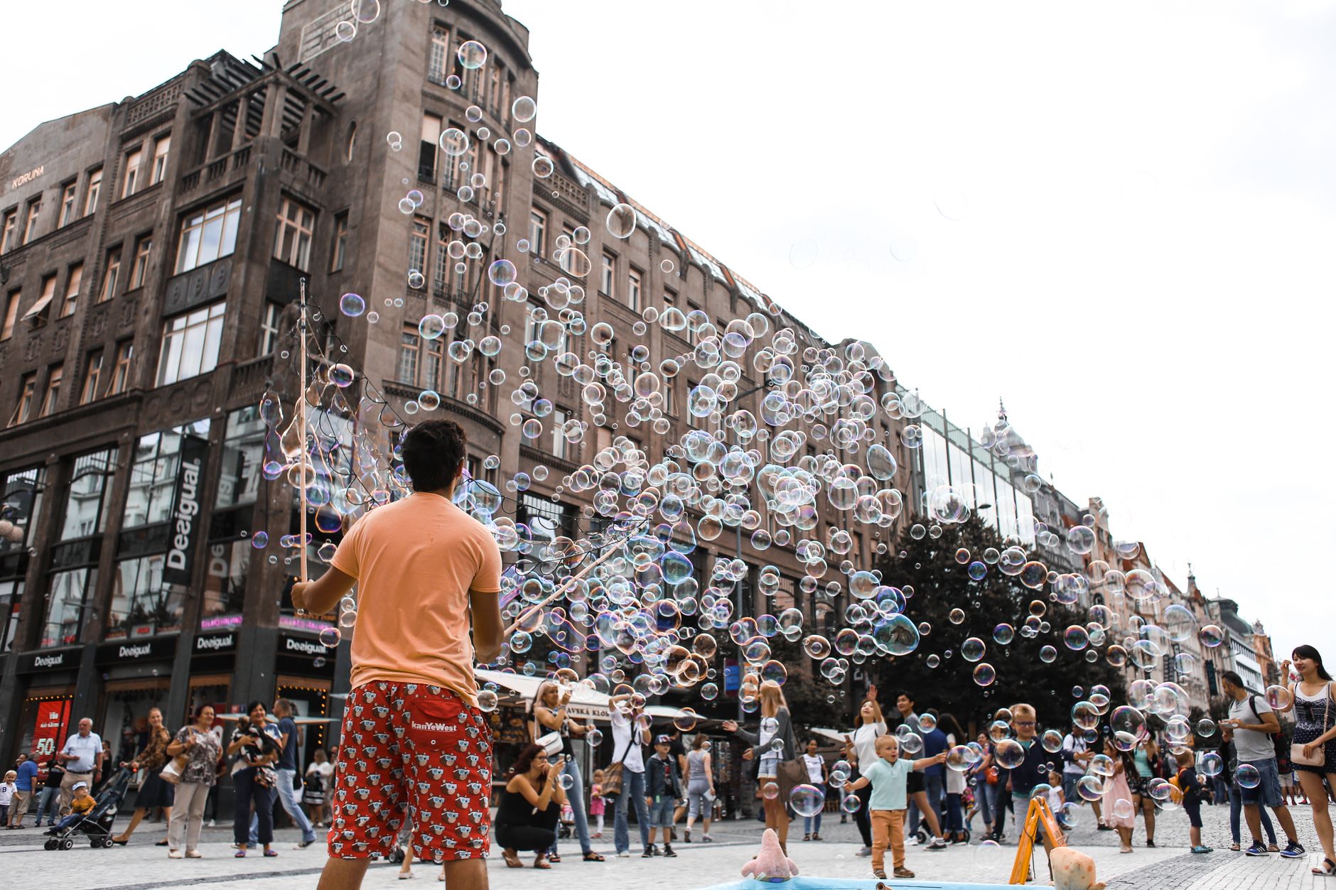 A street performer entertaining a crowd with soap bubbles in a bustling urban square, showcasing lively city life.