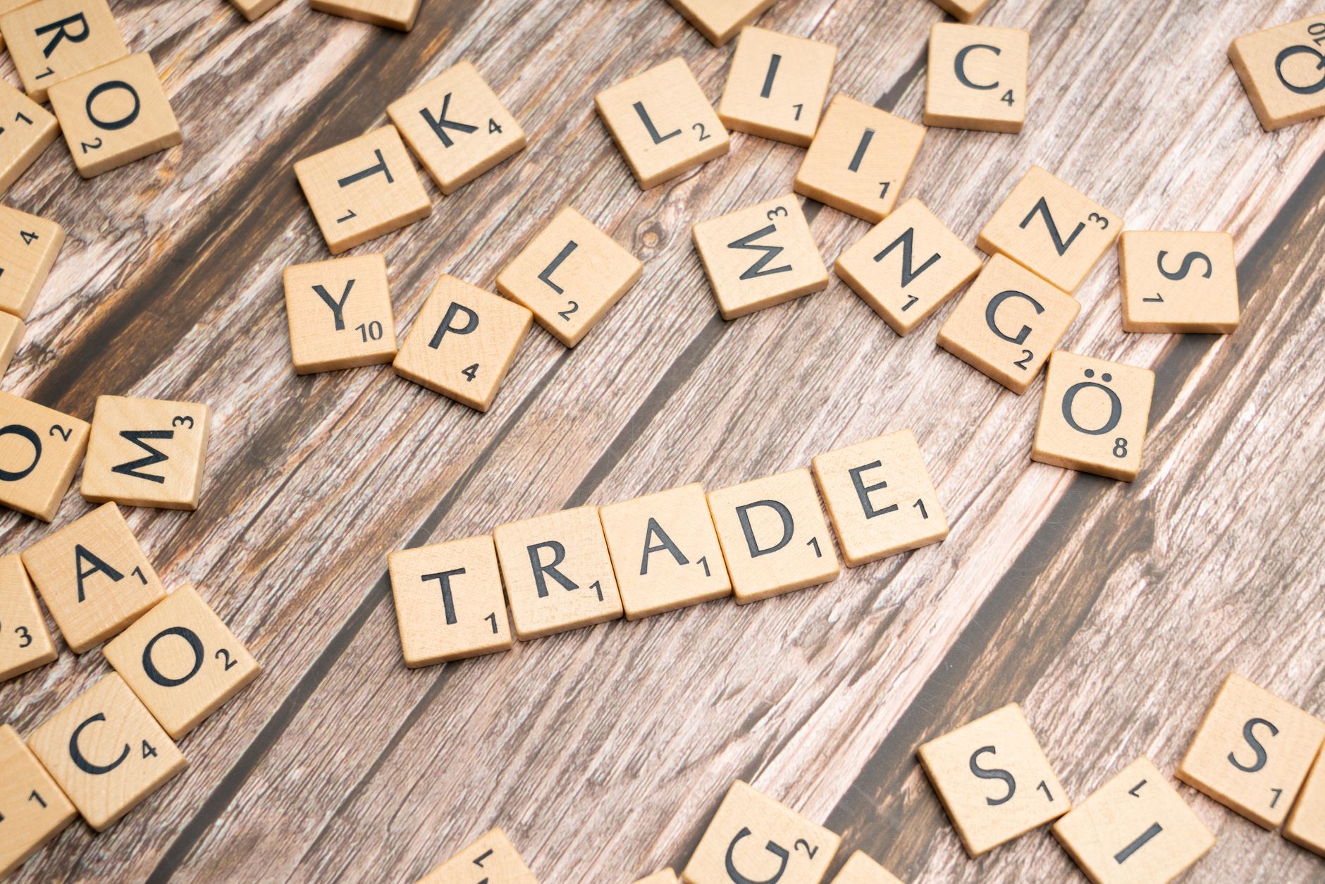 Scrabble letter tiles spelling 'trade' on a wooden surface, illustrating business concepts.