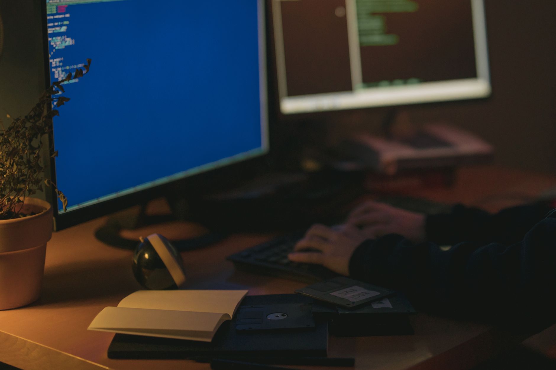 Individual programming in a dimly lit room with dual monitors.