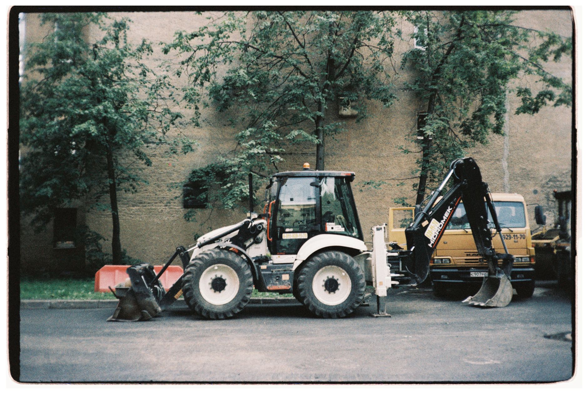 Tractor and backhoe parked outdoors on a city street.