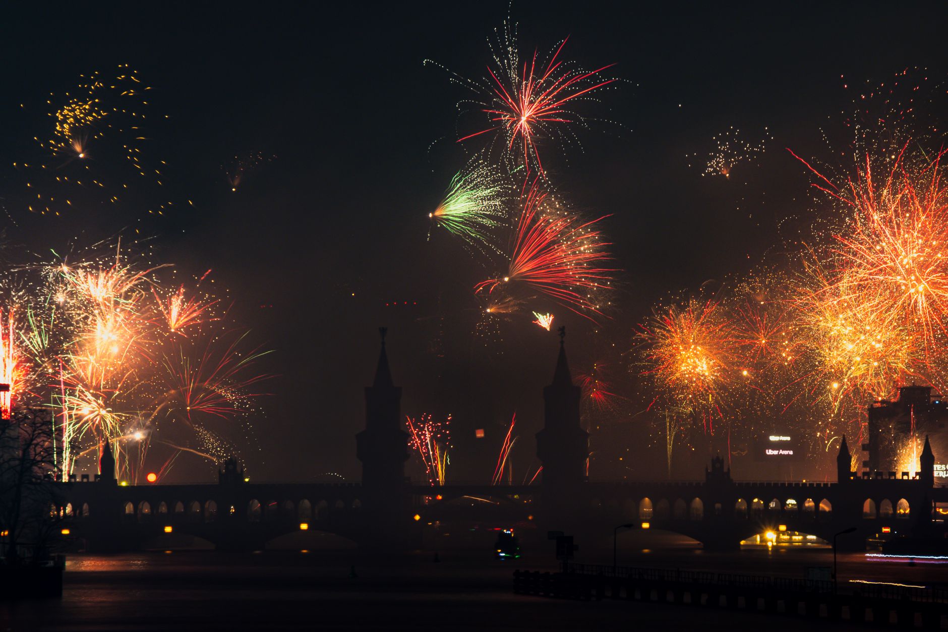 Vibrant fireworks illuminate the night sky over the Oberbaum Bridge in Berlin, capturing a festive cityscape.