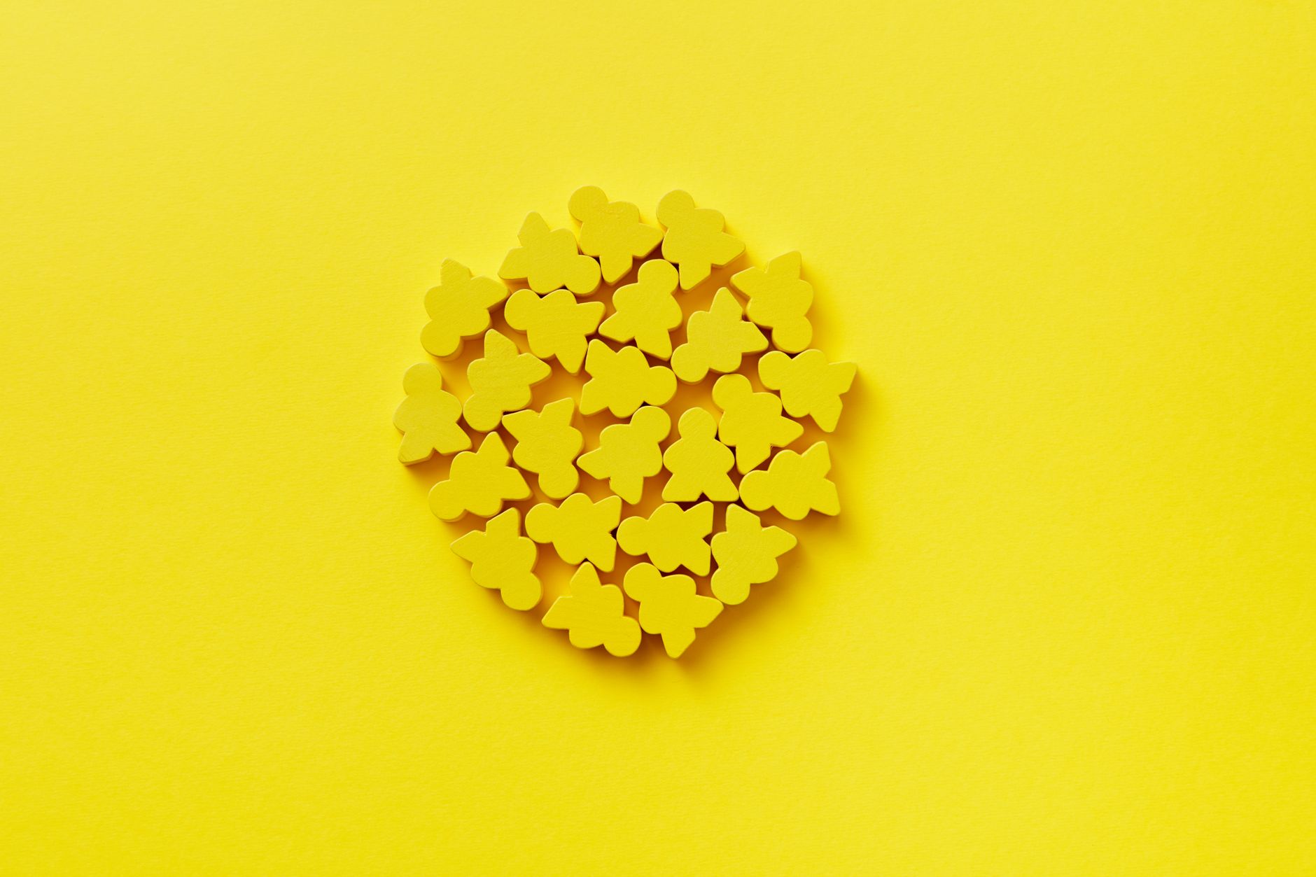 Vibrant yellow figurines arranged in a circle on a matching yellow background, creating a bold, minimalist design.