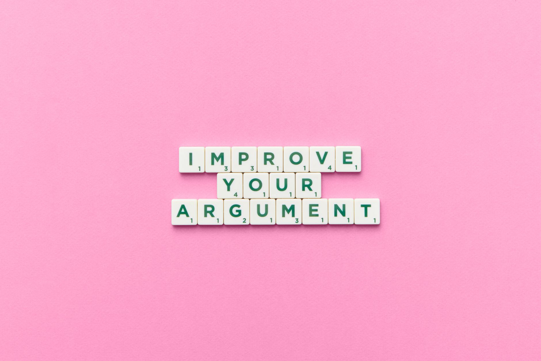 Scrabble tile letters spelling 'Improve Your Argument' on a pink background.