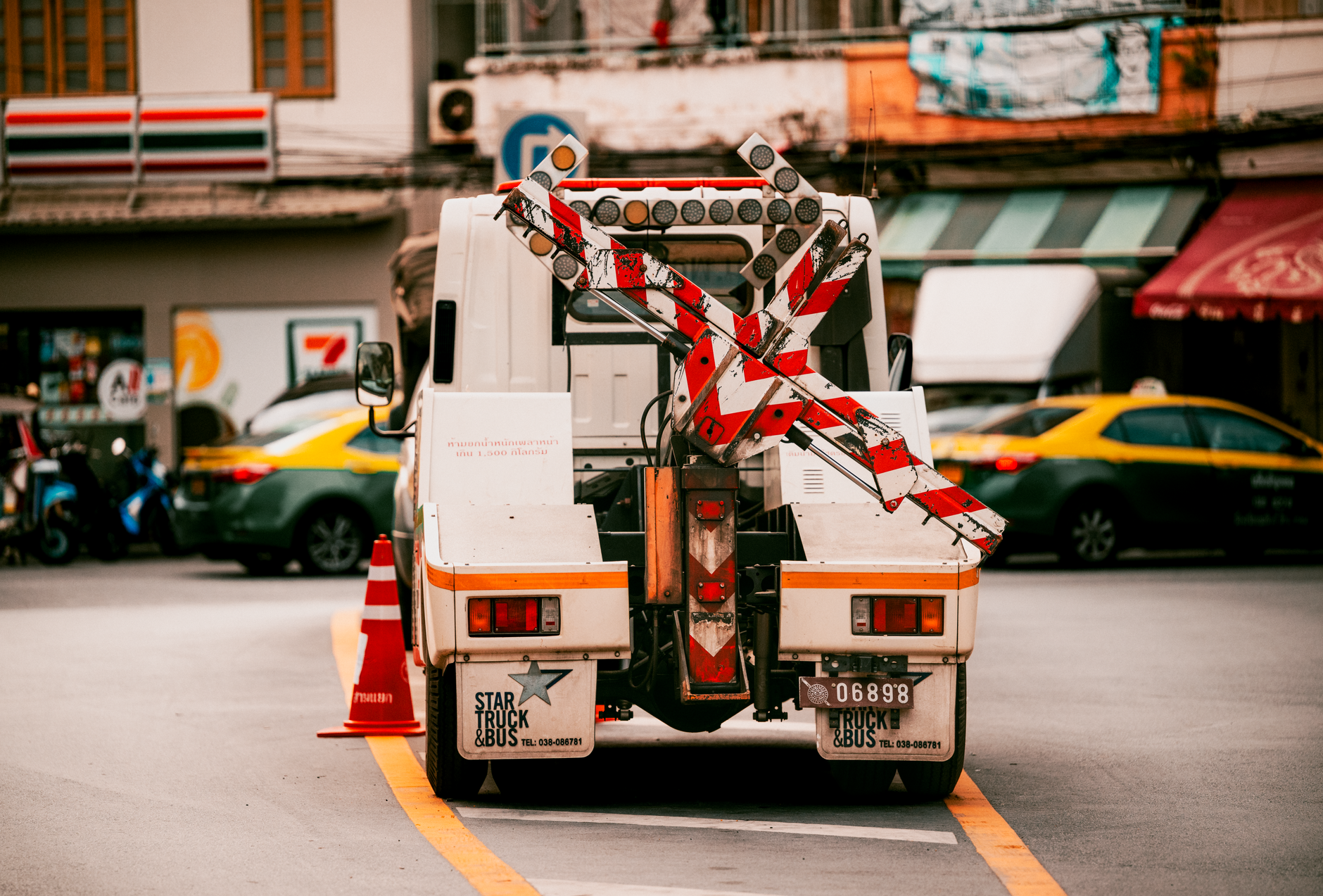Utility vehicle with traffic barriers on a busy street in Bangkok, Thailand.