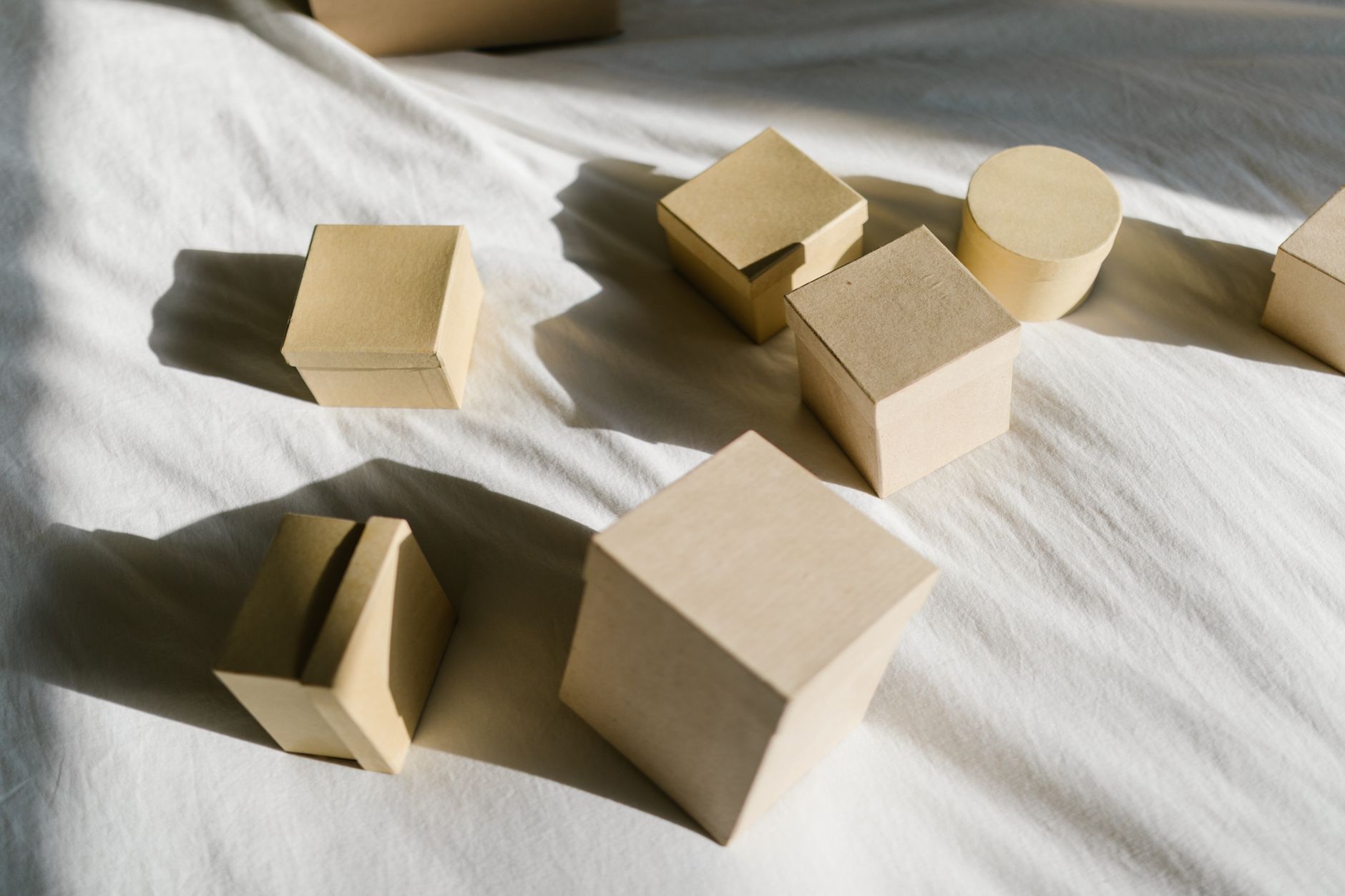 Close-up of cardboard boxes casting shadows on a sunlit fabric surface.