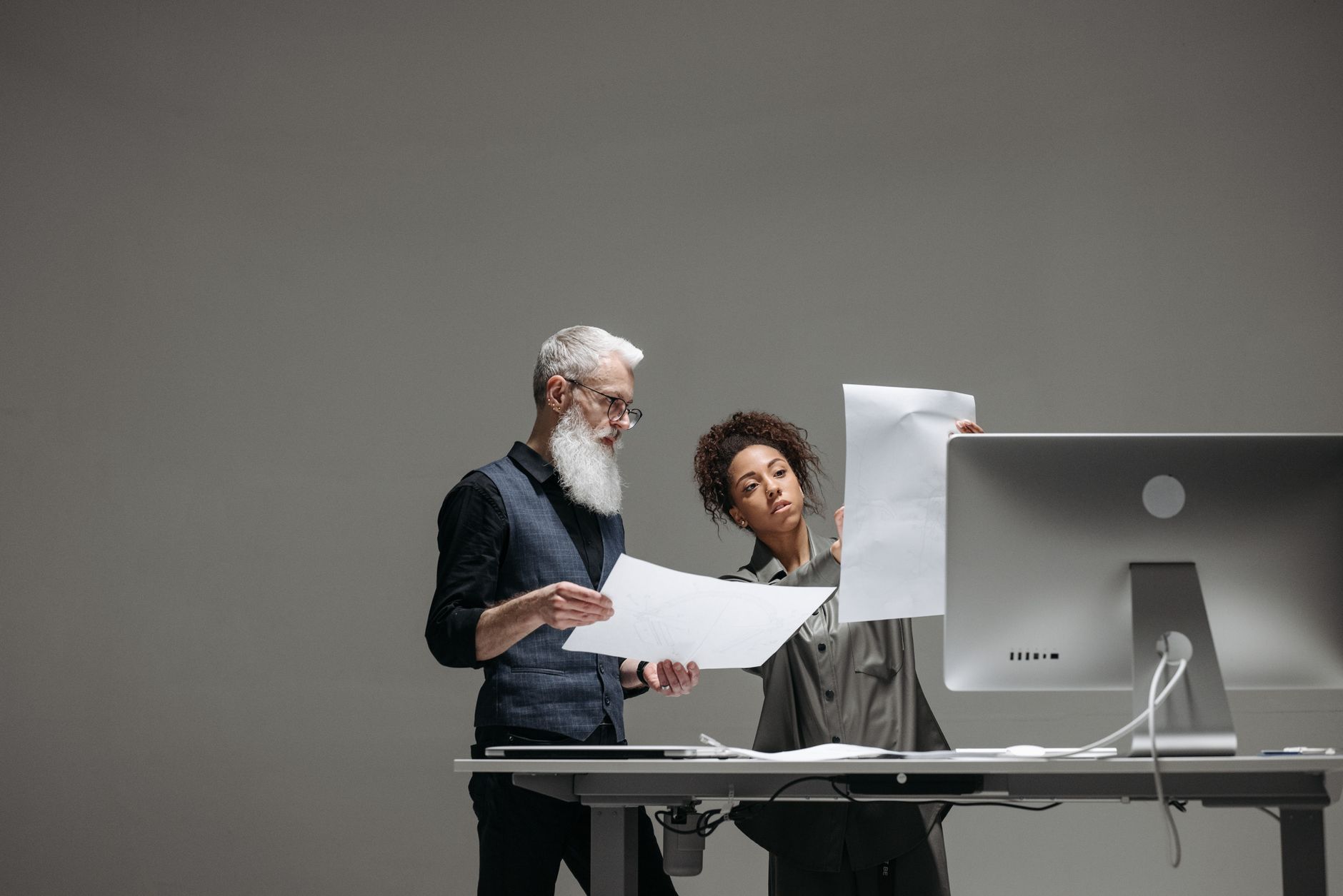 Two professionals collaborate on project plans at a computer workstation.