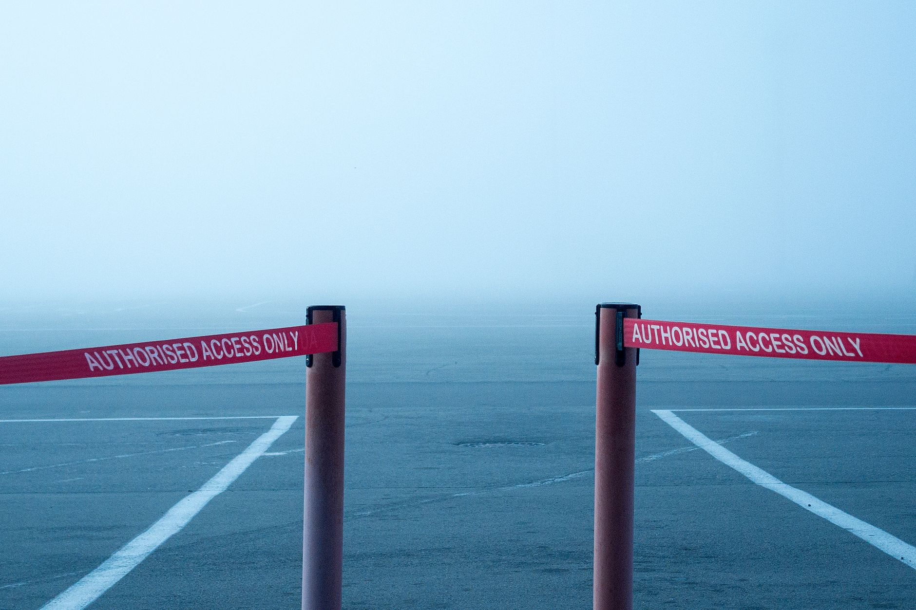 Misty airport runway blocked by safety barriers for authorized access only.