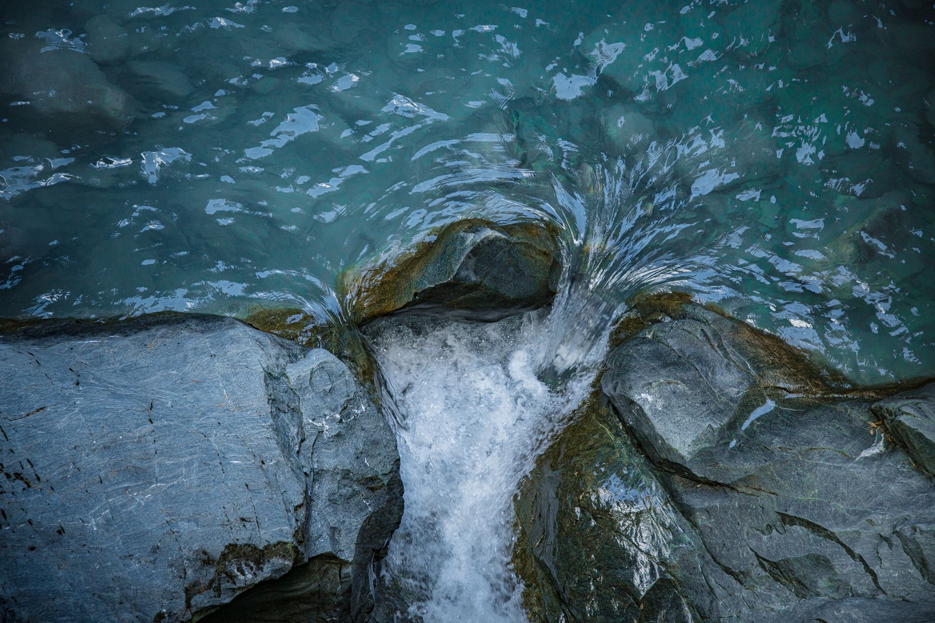 A scenic view of pristine waters flowing between rocks in Zermatt, capturing nature's tranquility.