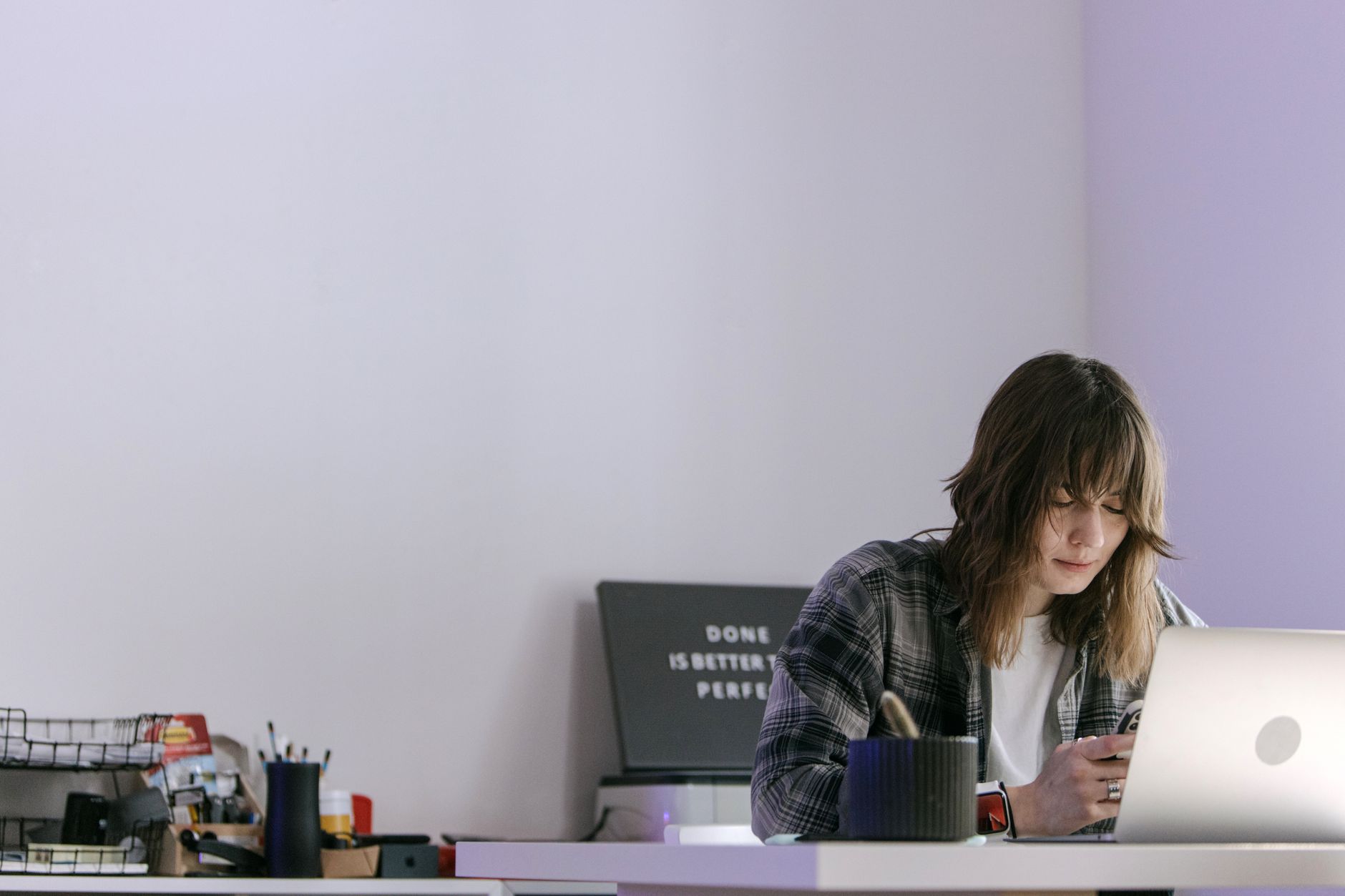 Young professional using a smartphone at a desk in a modern office setting.