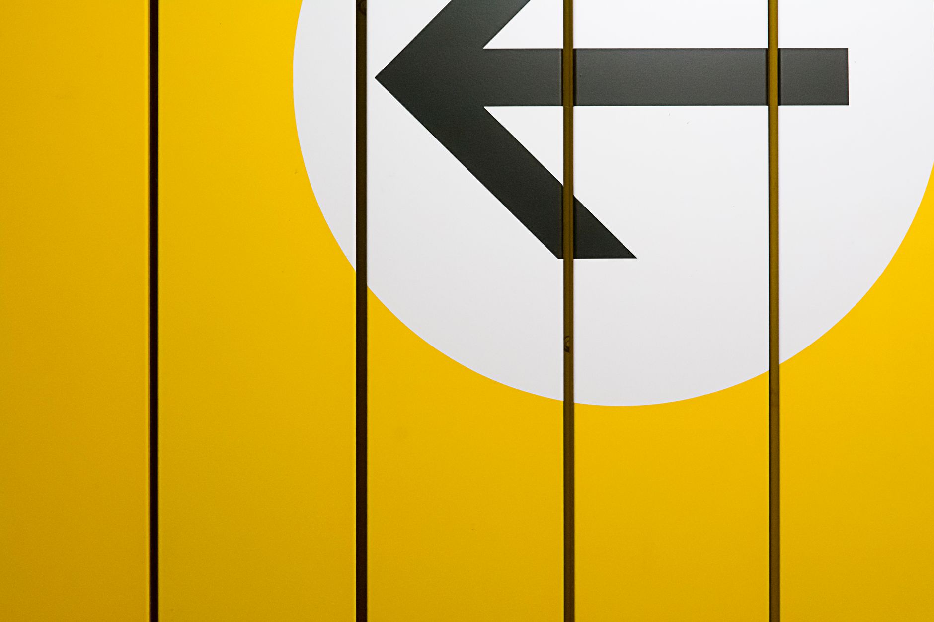A minimalist design featuring a bold black arrow on a vibrant yellow background, symbolizing direction.