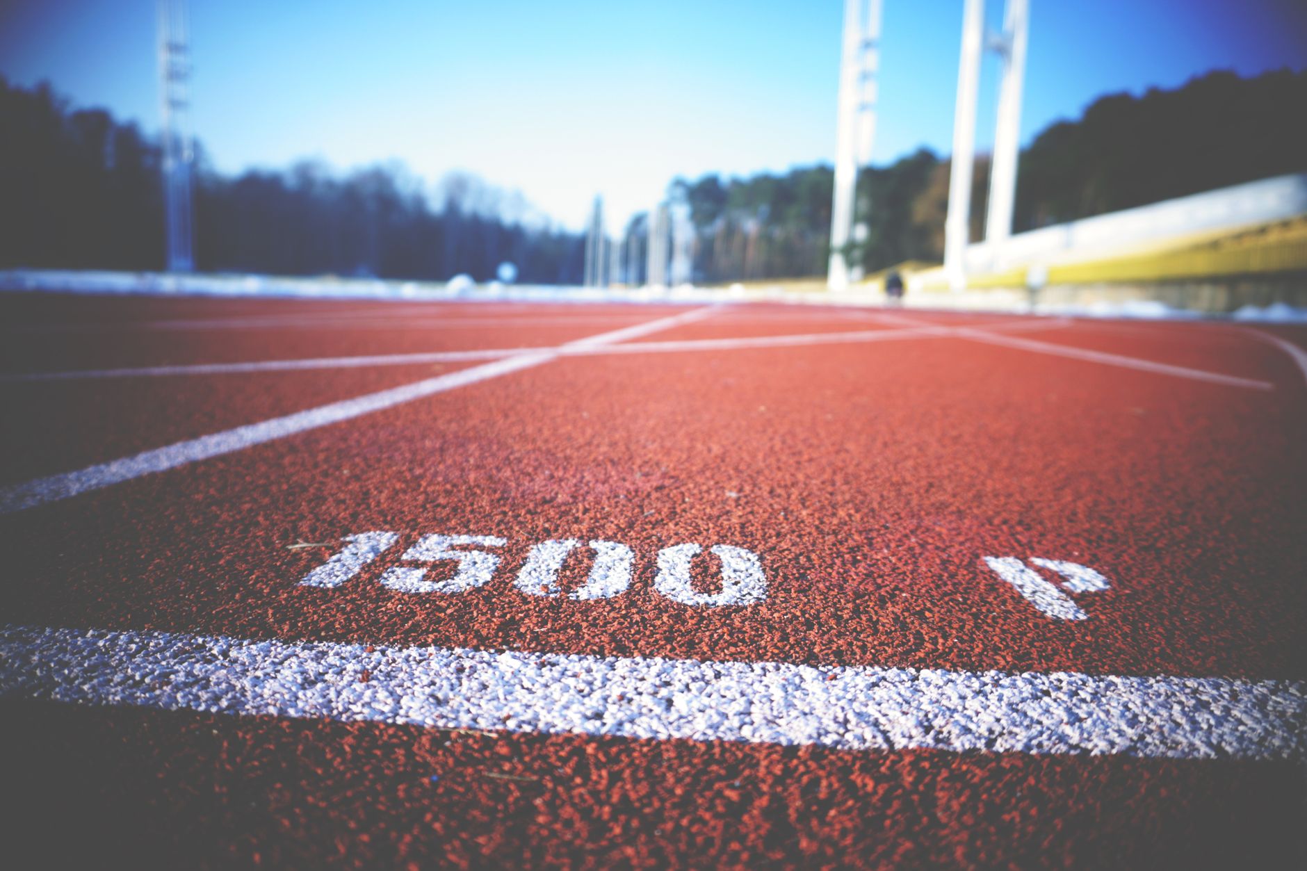 Empty running track lane with 1500 meter marking, sunny day outdoors.