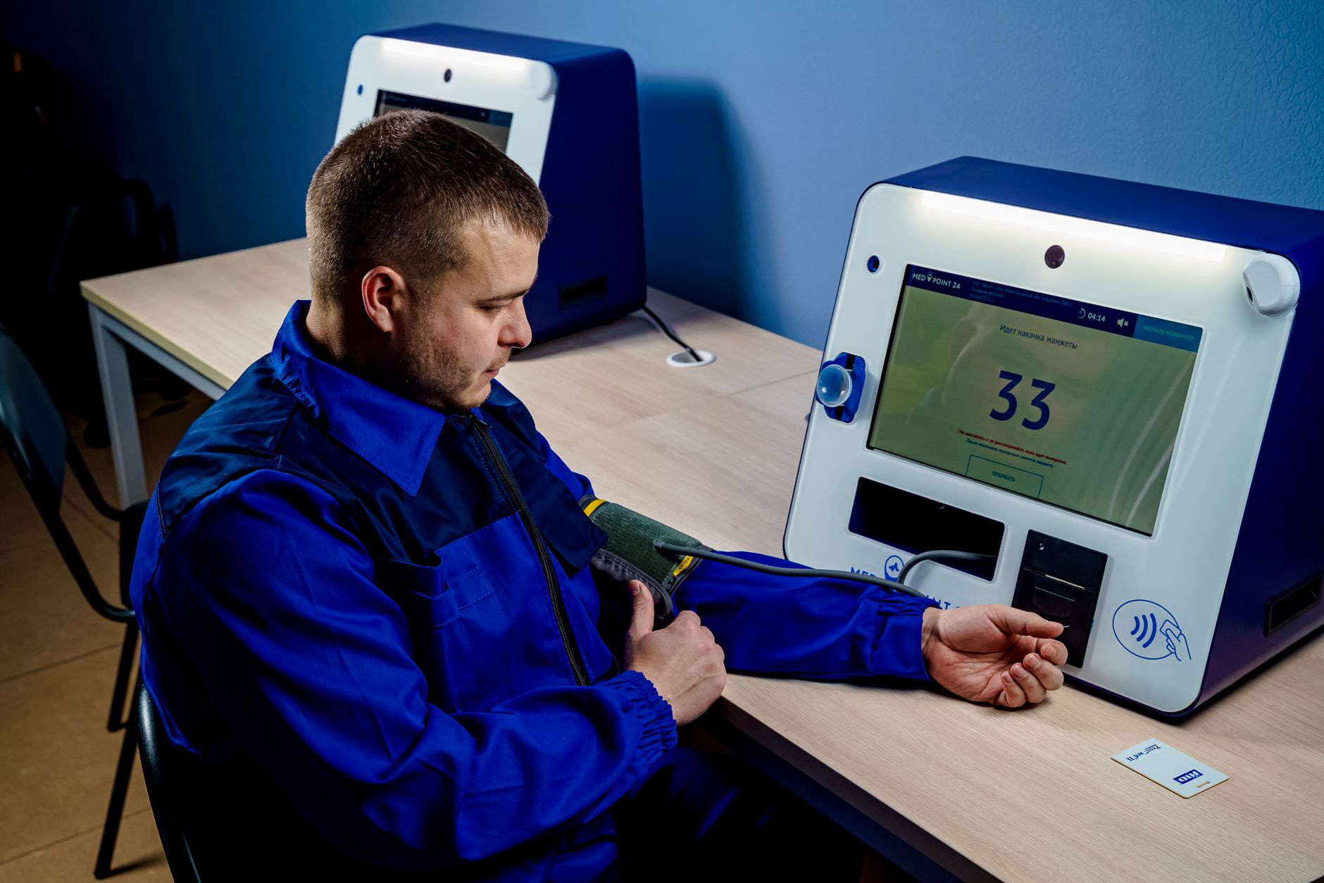 A man uses a modern machine to measure his blood pressure indoors.