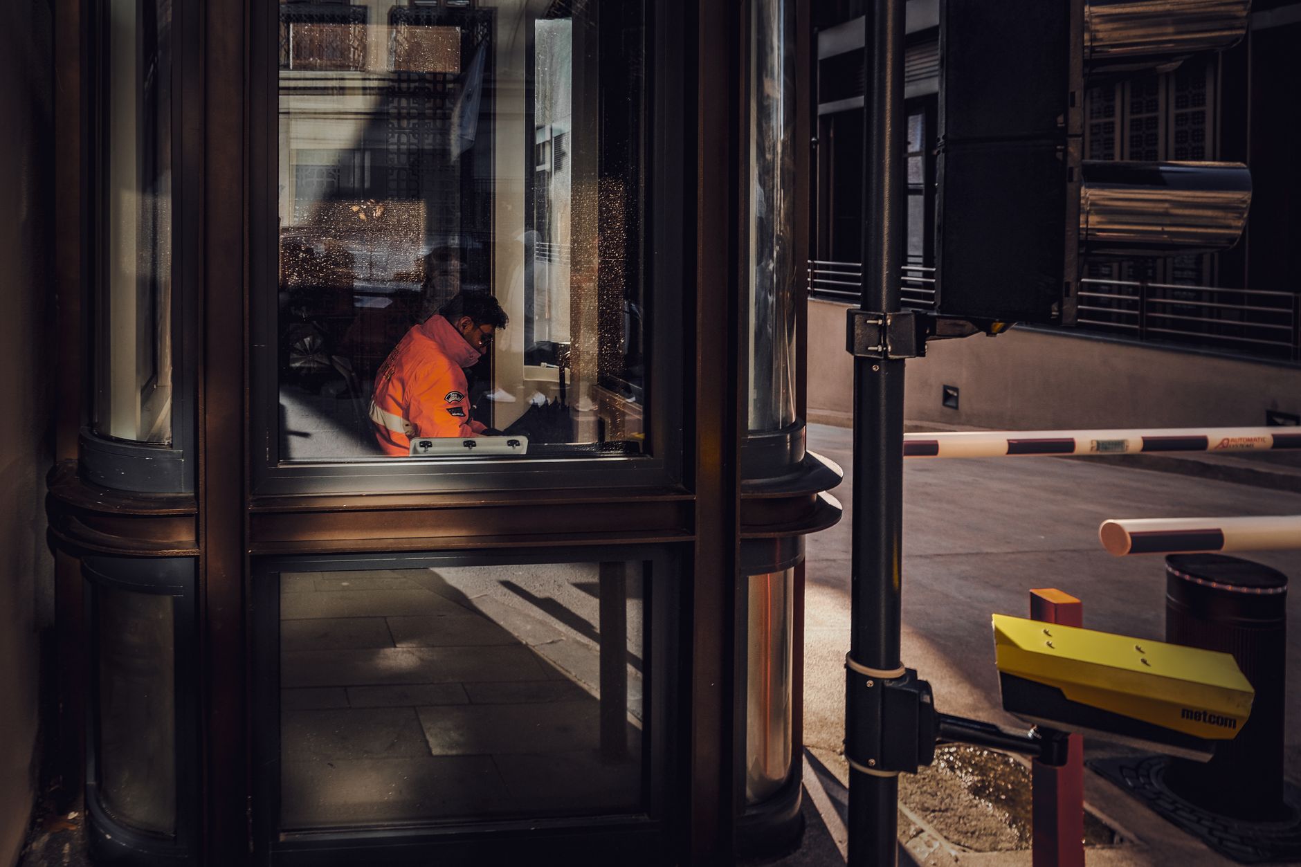 A security guard sitting inside a glass booth in Istanbul, Türkiye.