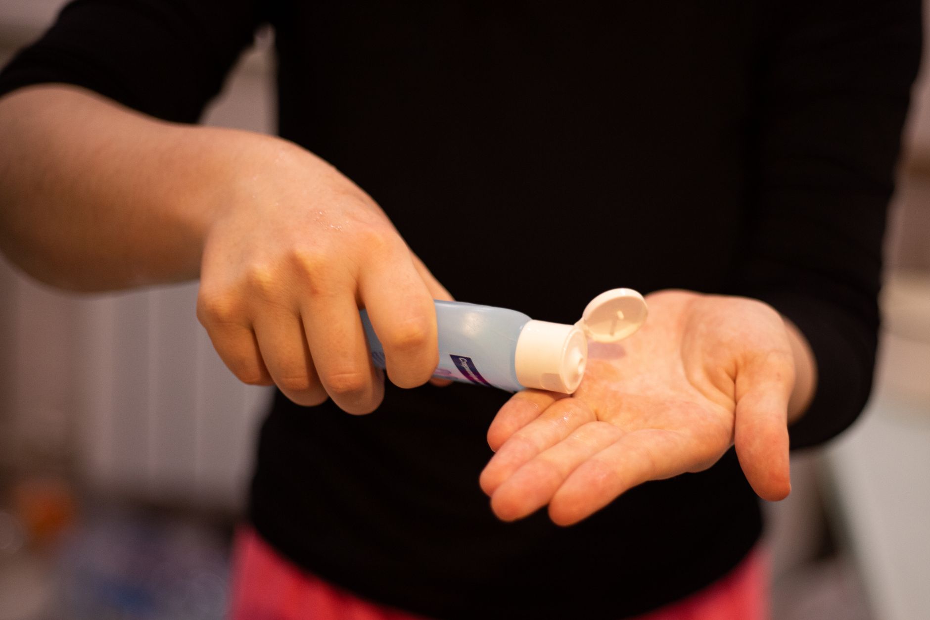 A close-up image of a woman applying hand sanitizer to maintain hygiene.