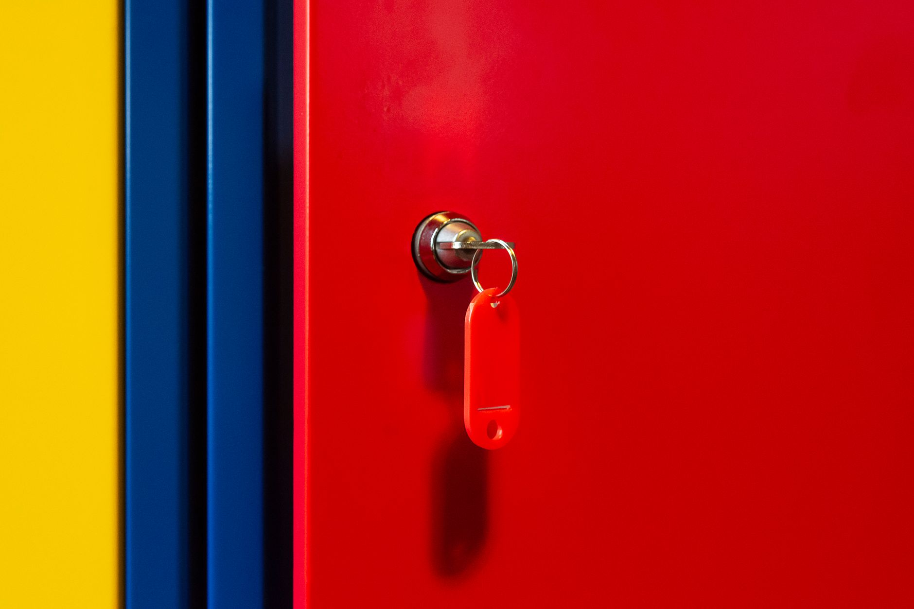 A vibrant image of a red locker door with a key in the lock, featuring bold primary colors.