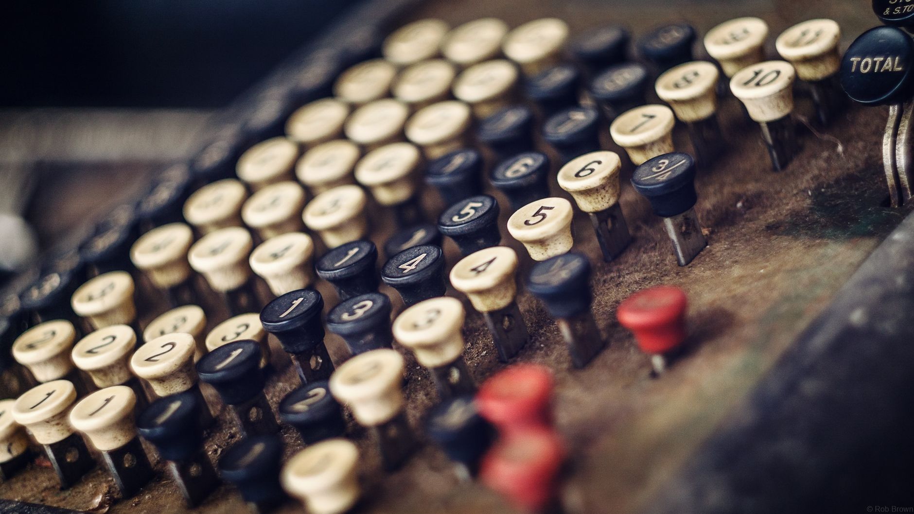 Close-up photo of an antique cash register with numbered keys in a retro style.