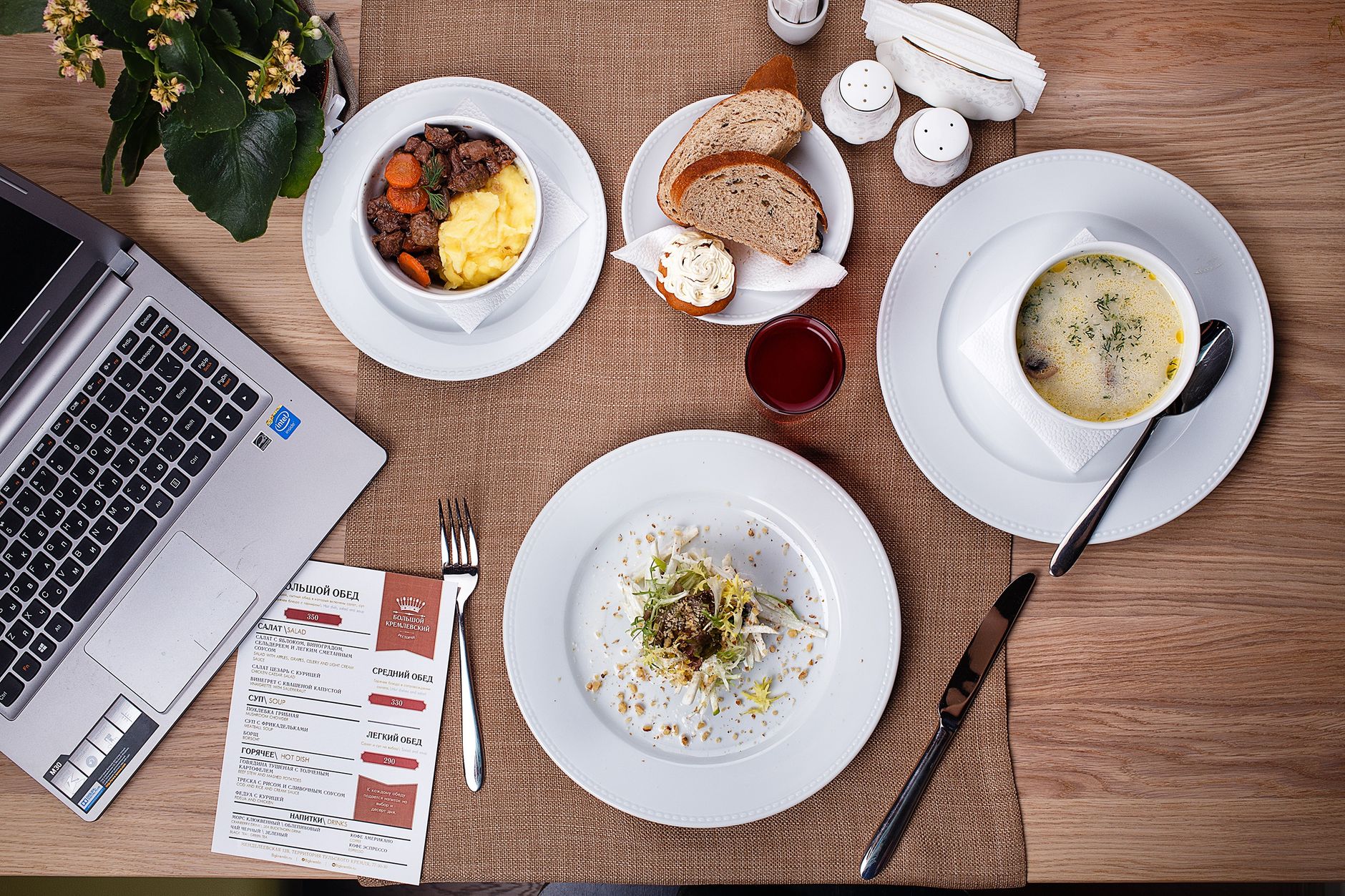 An overhead shot of a meal setup with laptop, showcasing food and productivity in a cozy indoor setting.