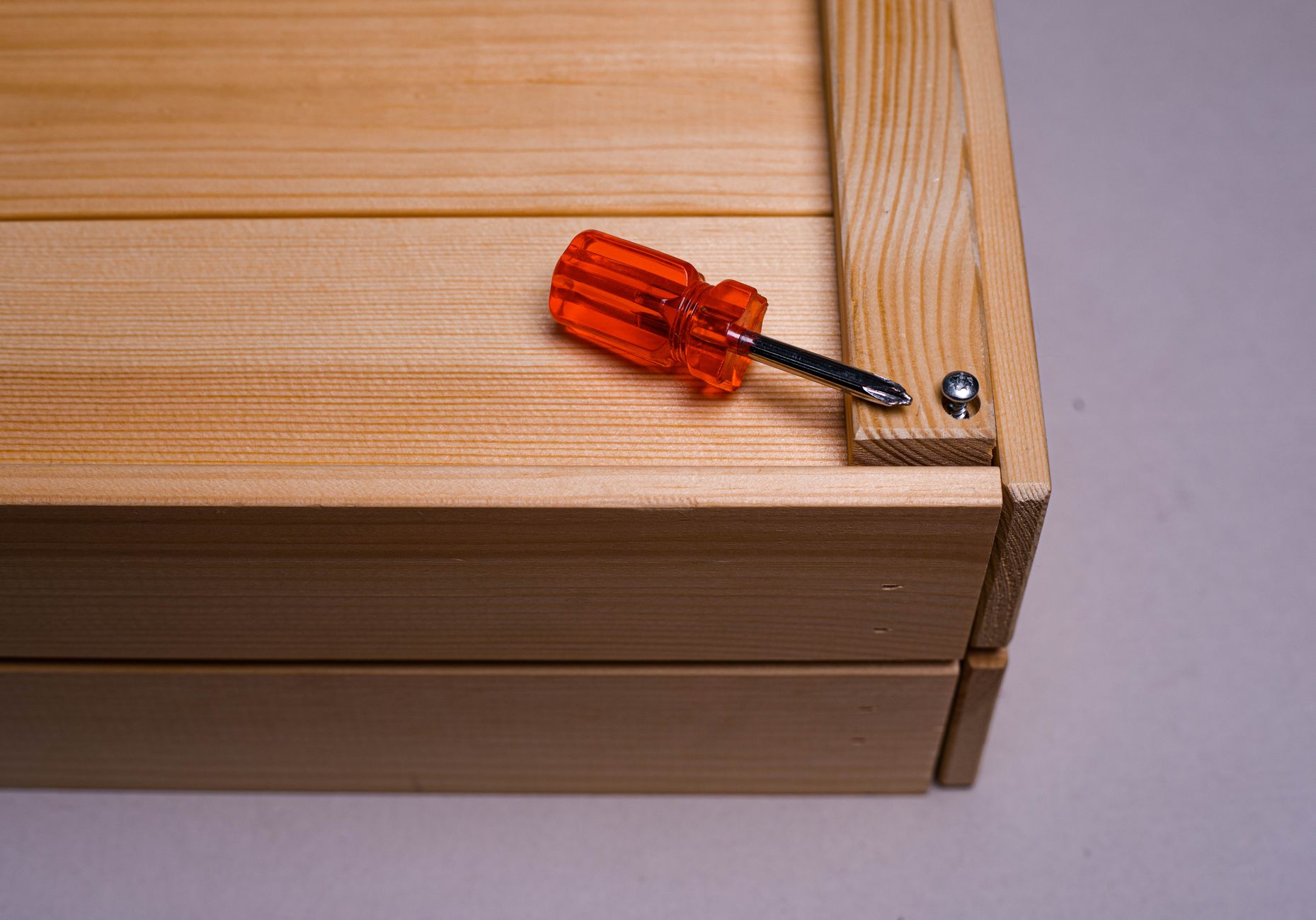 A close-up of a screwdriver on a wooden box, highlighting DIY and home improvement tools.
