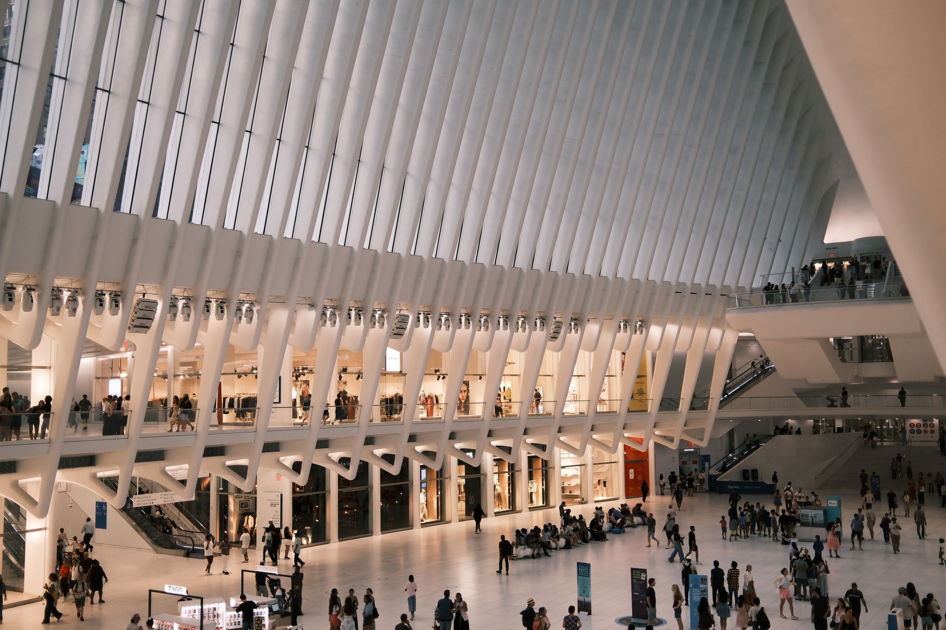 Bustling interior view of The Oculus in New York City with people shopping and socializing.