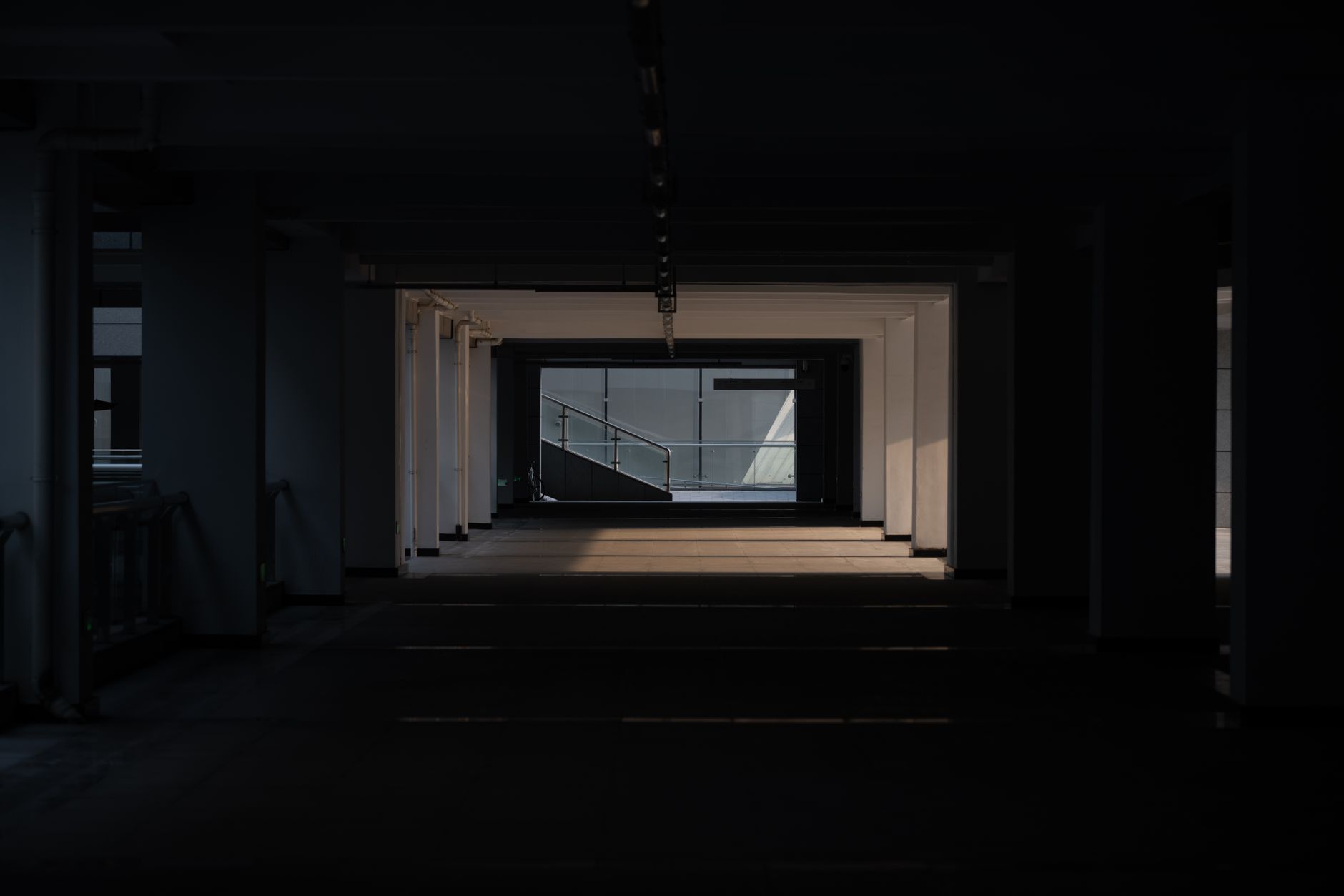 A moody view of a dimly lit urban architectural corridor, creating a dramatic and mysterious atmosphere.