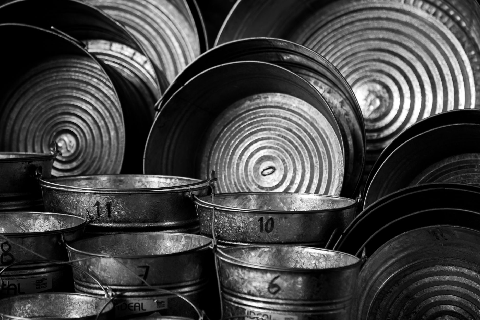 Artistic black and white photo of metal buckets with numbers showcasing industrial design.