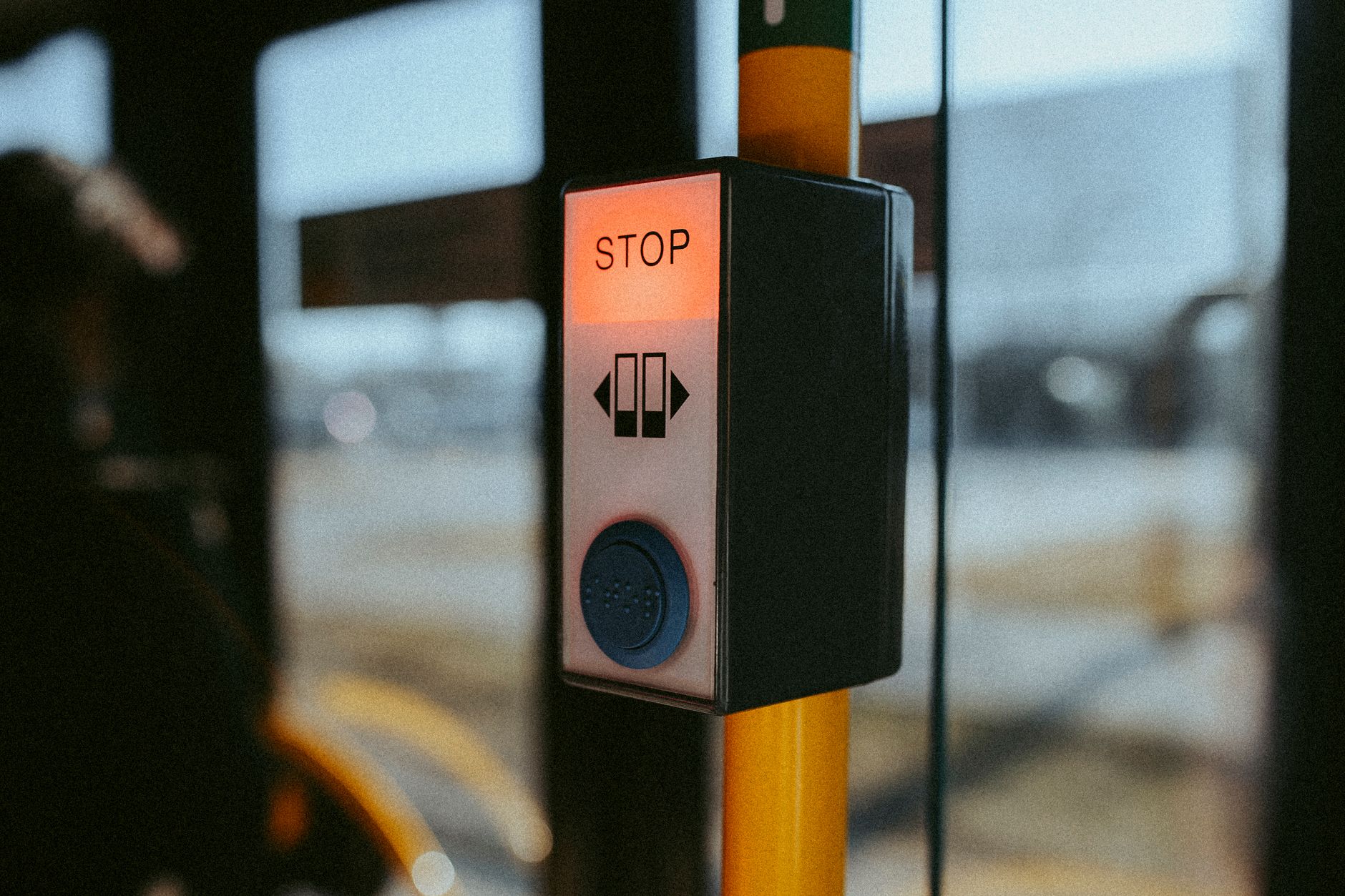 A close-up of a stop button on a public bus, highlighting travel and safety features.